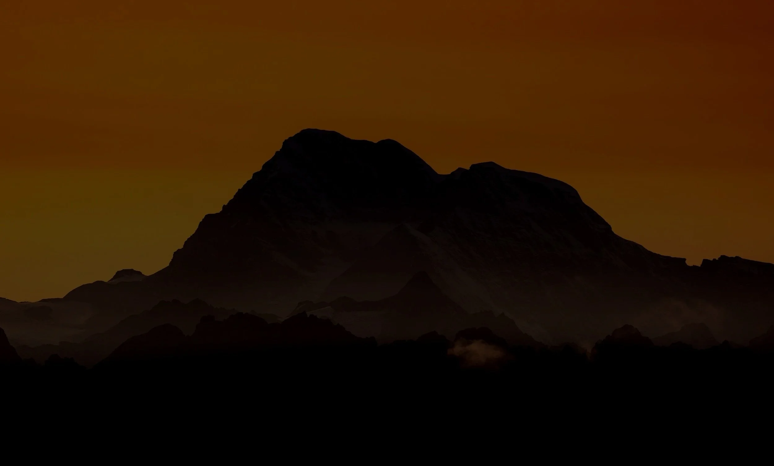 Silhouette of a mountain range during sunset with an orange sky.