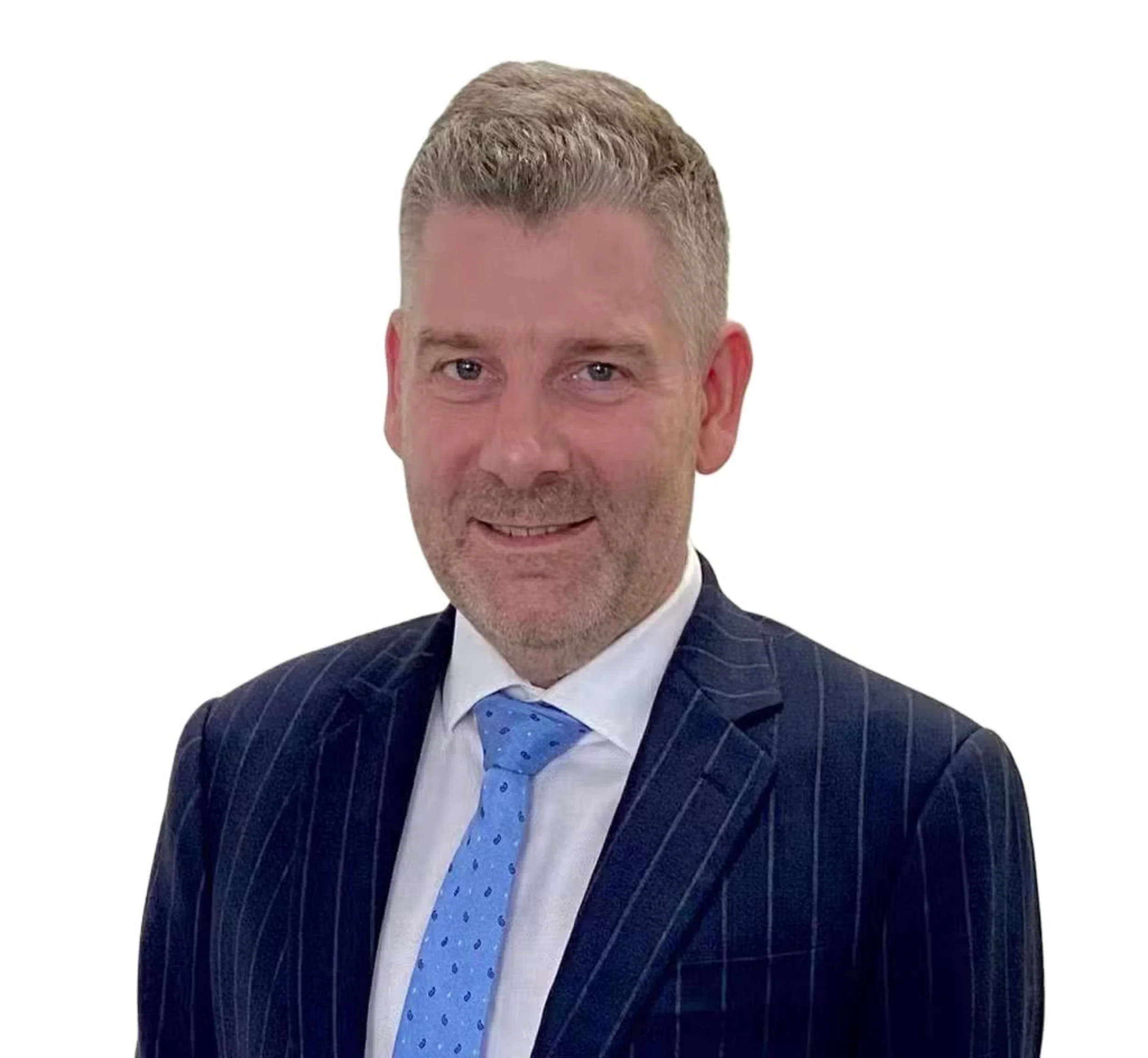 Faysal with short gray hair, light beard, wearing a dark pinstripe suit, white shirt, and blue tie, smiling in front of a plain white background.
