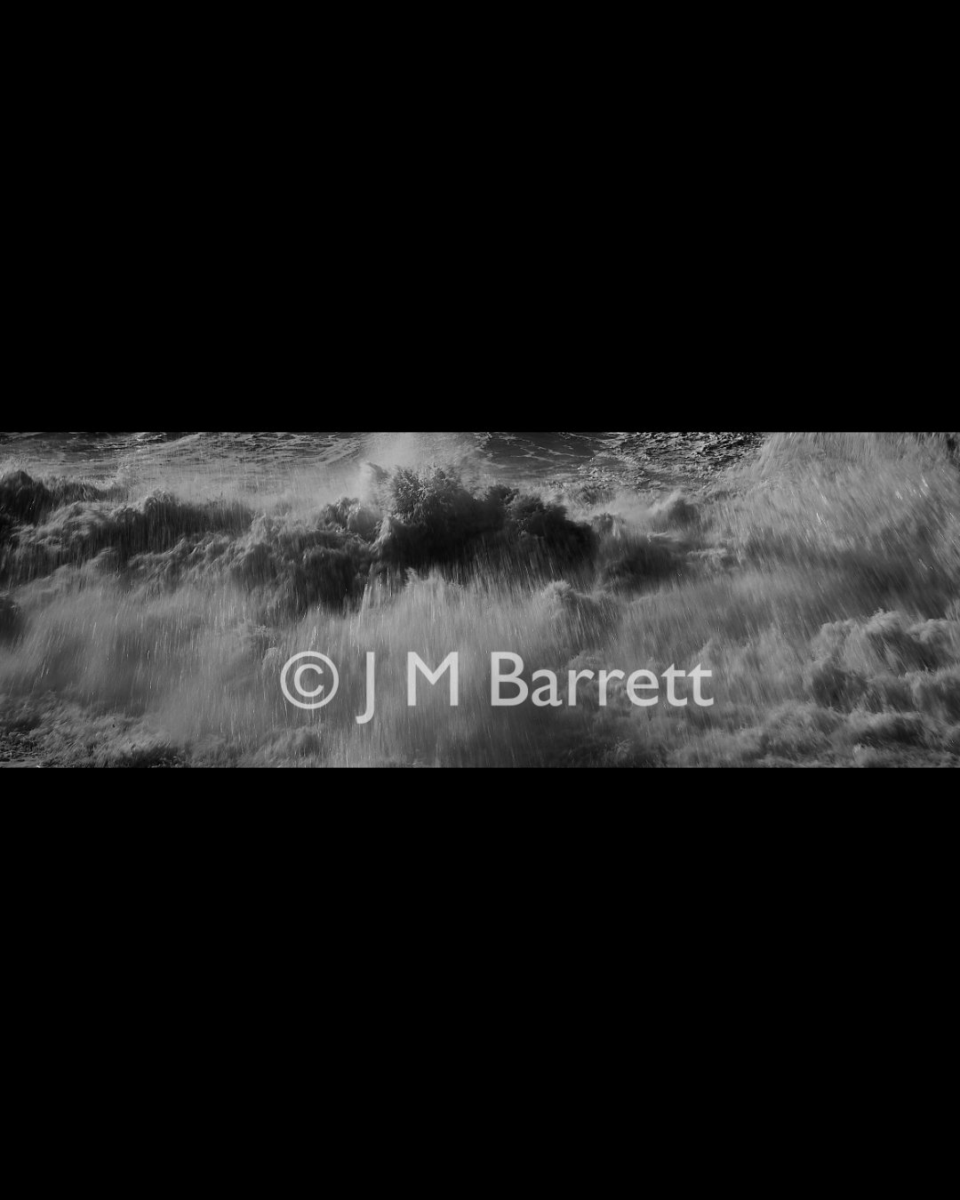 Black and white photo of ocean waves crashing with the text '© J M Barrett' overlaid.