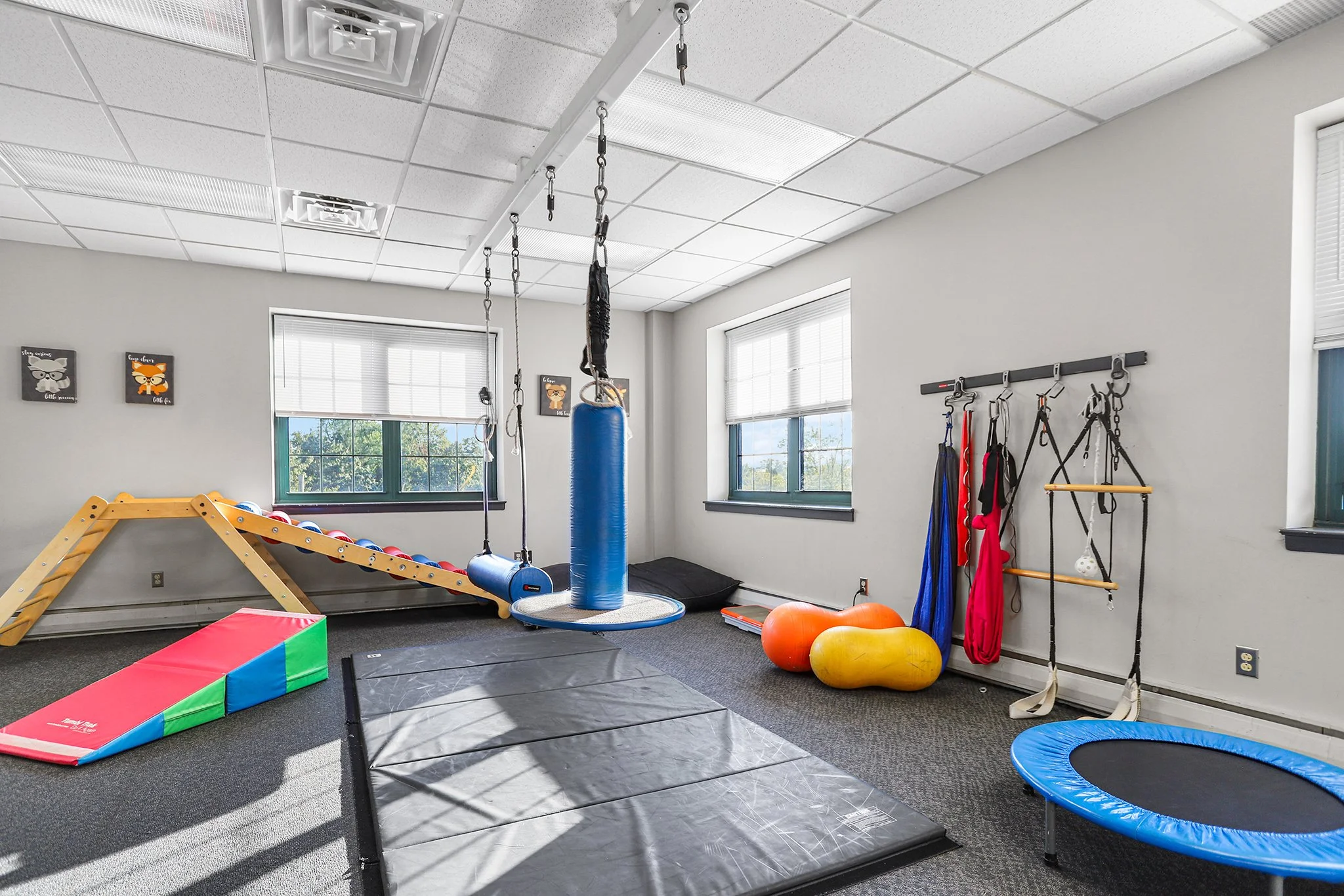 Indoor gym with soft mats, balance toys, punching bags, and exercise equipment for children.