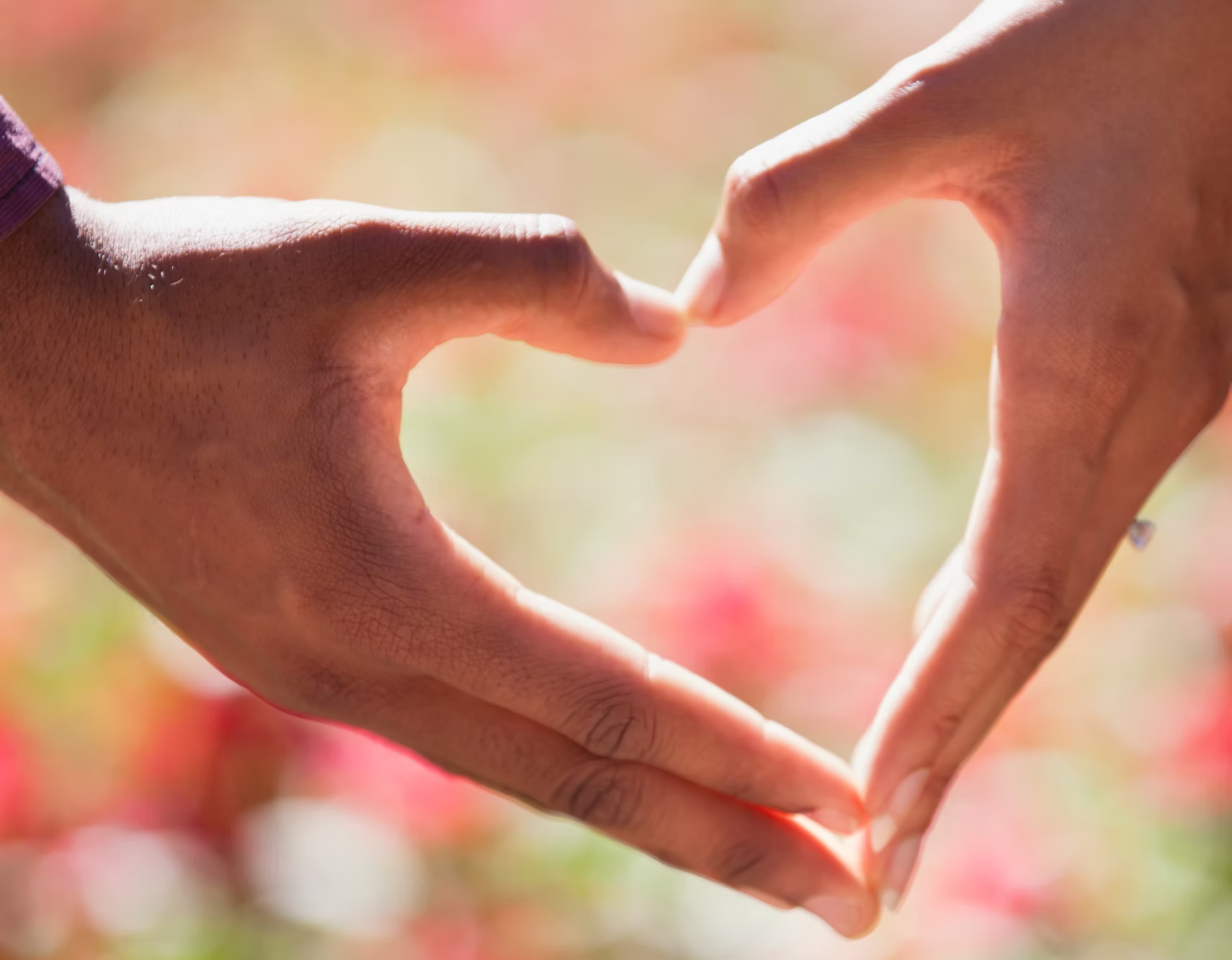 Two people forming a heart shape with their hands.