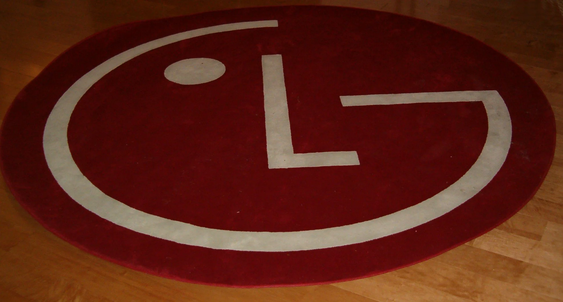 Red oval sign with white text 'L' and a white circle, placed on a wooden floor.