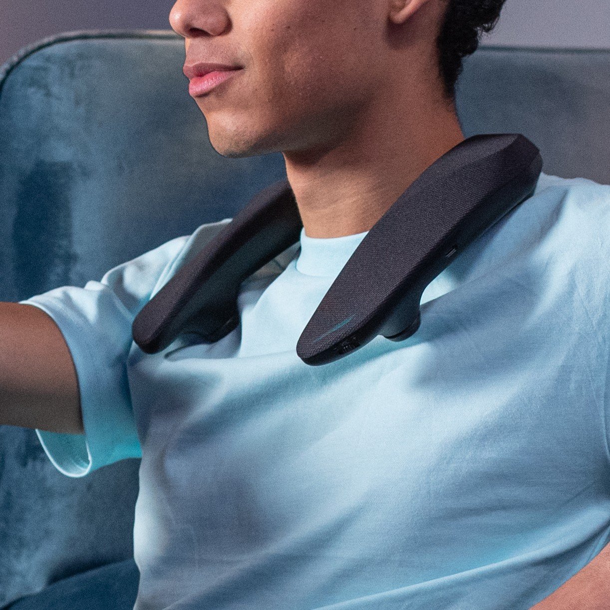 Person wearing a neck massage device while sitting in a chair.