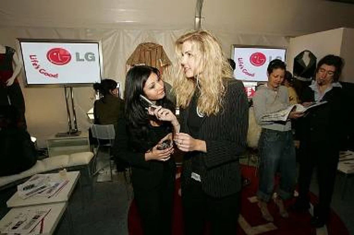 Two women having a conversation at a business event with LG branding on screens in the background.