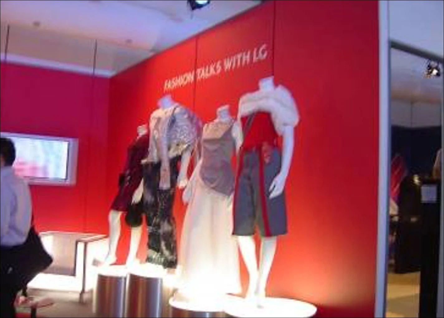 Three mannequins displaying fashion outfits on white platforms against a red wall with white text that reads 'Fashion Talk with LG'.