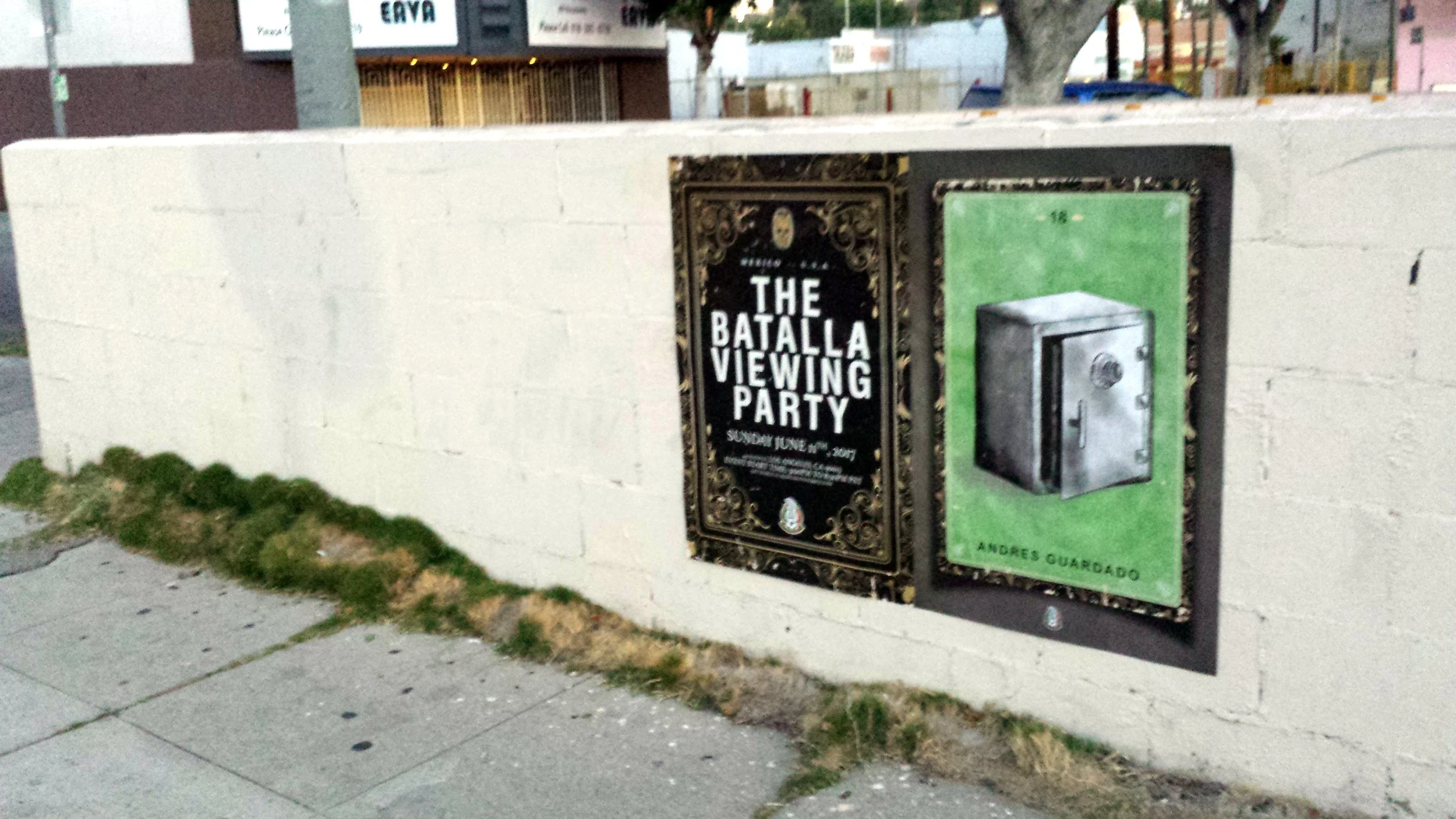 A white brick wall with two posters attached; one advertises THE BATALLA VIEWING PARTY, and the other shows an image of a safe with the name ANDRES GUARDADO.