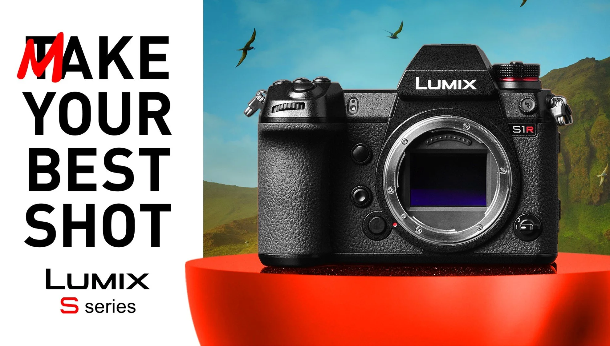 A Panasonic Lumix S1R camera without a lens, positioned on a red cylindrical platform with a scenic background of a blue sky, green hills, and flying birds.