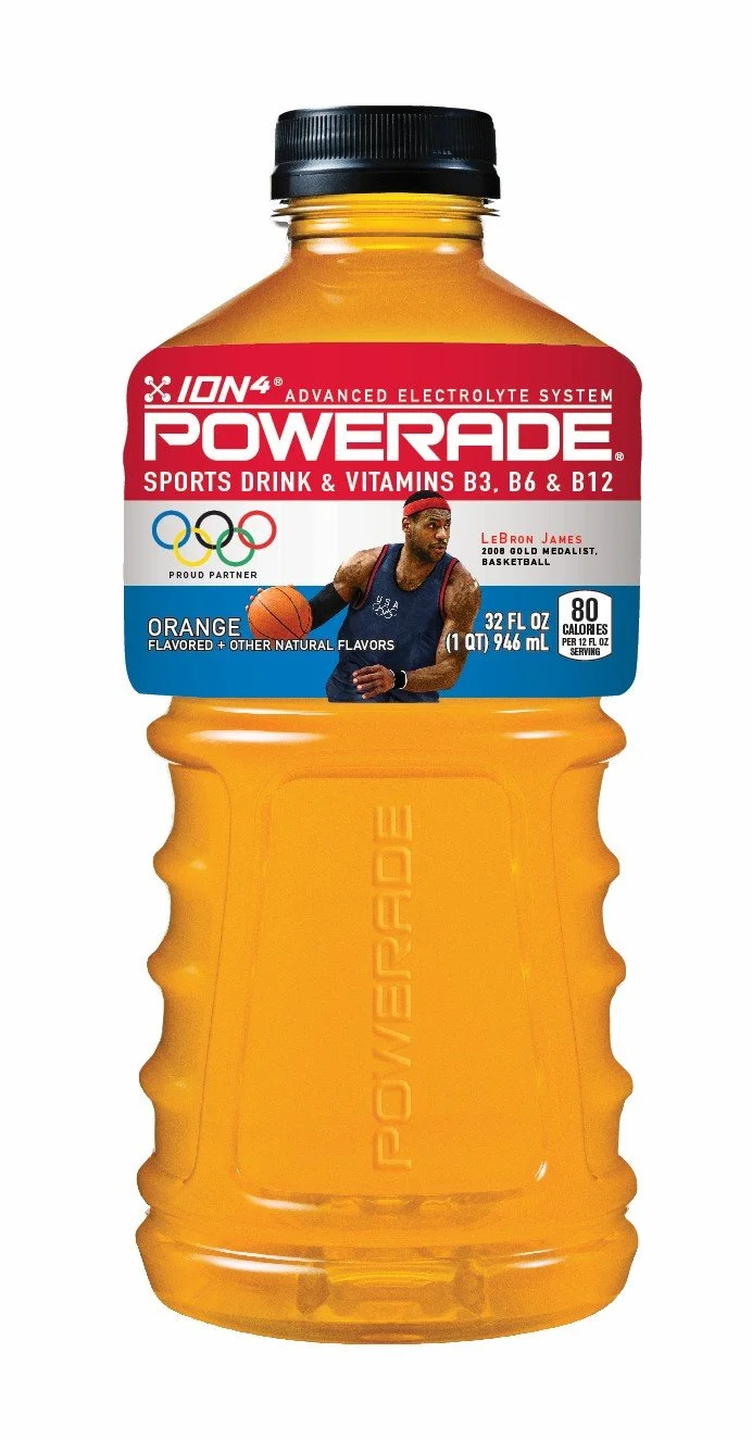 A bottle of Powerade sports drink with orange flavor. The label features LeBron James, Olympic rings, and mentions electrolytes, vitamins B3, B6, and B12.