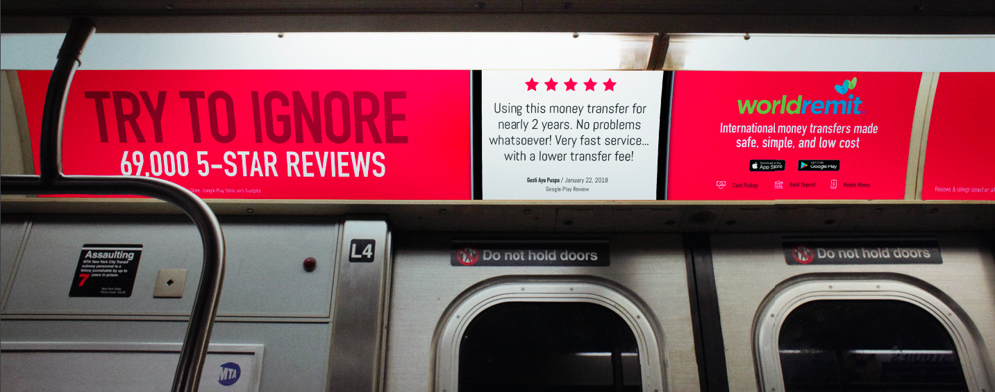 Advertisement on subway wall promoting a money transfer service called WorldRemit, featuring red and white backgrounds, text indicating customer reviews and benefits, and app store logos.