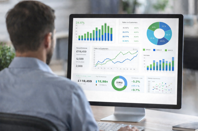 A man works on a computer displaying various business analytics and performance graphs.