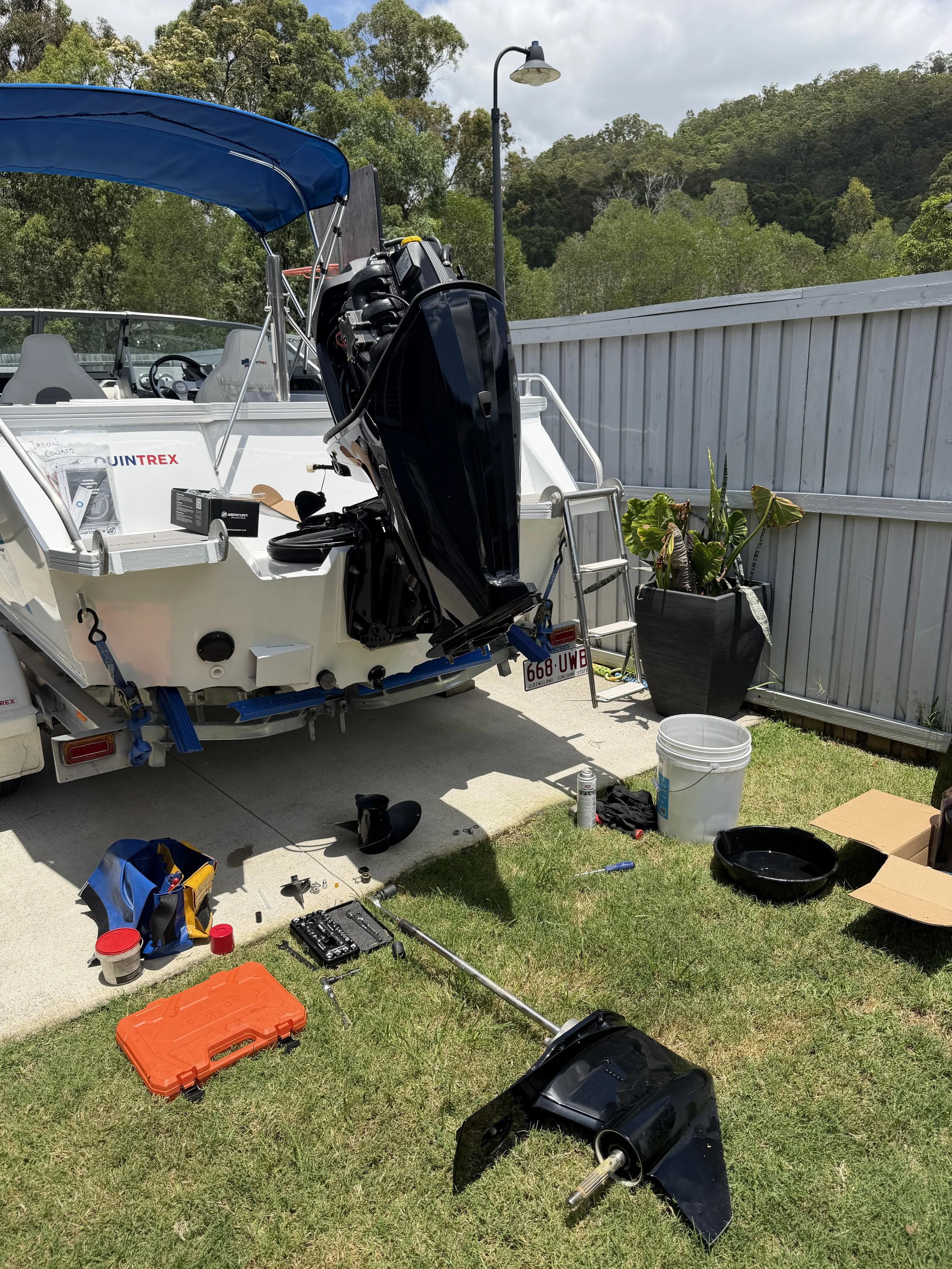 A outboard engine being serviced in a driveway. Leg is off to replace waterpump.