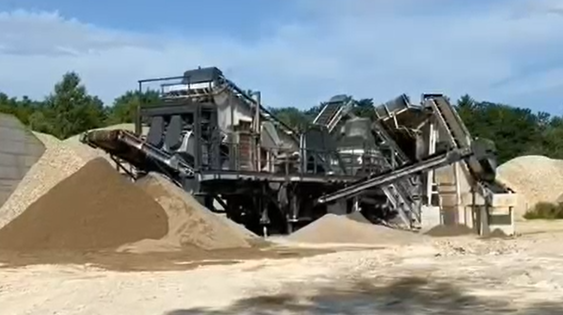 A large portable sand crushing, screening and washing with a feed hopper and discharge conveyors.