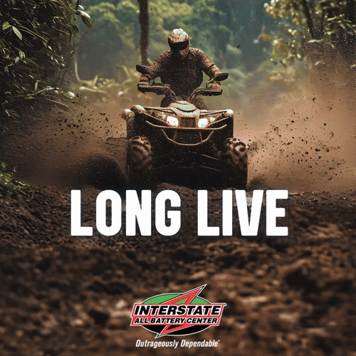 Person riding an ATV through a dirt trail in a forest, kicking up dust, with the text "Long Live" and the Interstate All Battery Center logo at the bottom.