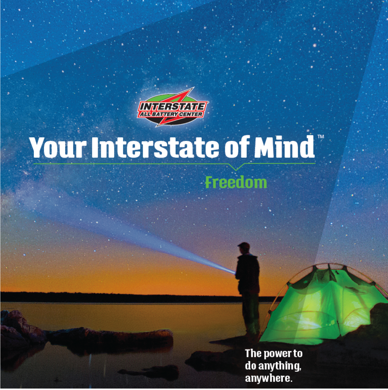 A person standing near a tent on a rocky shore at night, looking at the starry sky with a flashlight, with a flashlight beam pointing at the sky, and the reflection of the stars on the water. The image promotes Interstate All Battery Center with the 