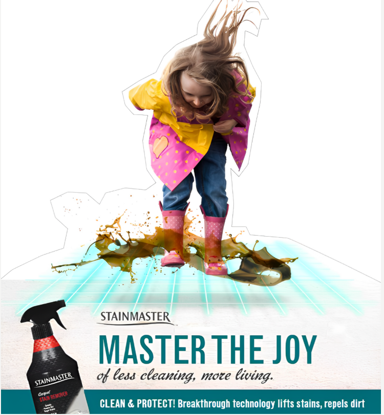 A young girl in pink rain boots and a colorful raincoat stomping through a spilled liquid stain on a tiled floor, with a bottle of StainMaster stain remover nearby.