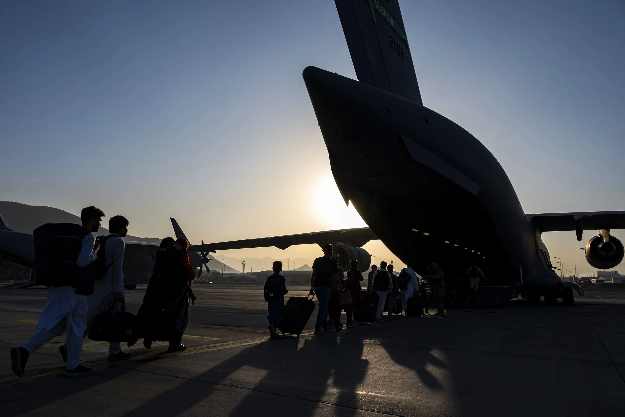 Airmen guide qualified evacuees aboard an Air Force C-17 Globemaster III while supporting the noncombatant evacuation operation at Hamid Karzai International Airport, Afghanistan, Aug. 24, 2021. The Defense Department is committed to supporting the S