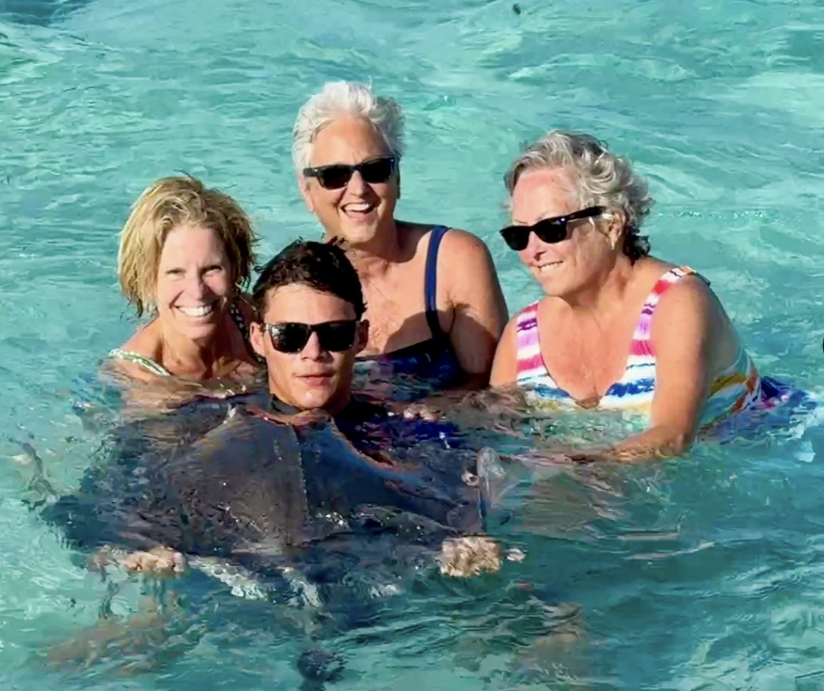 Guests in clear shallow water beside a stingray.