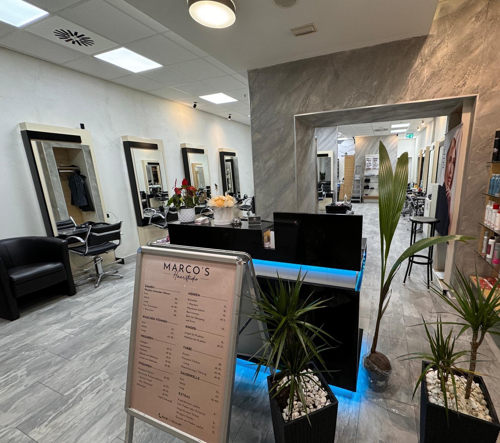 Innenansicht eines Friseursalons mit Waschbecken, Spiegel und Sitzbereichen.