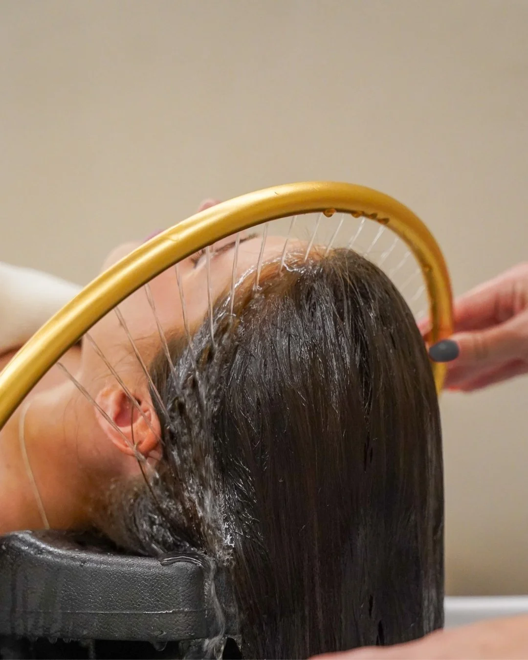Een persoon die een hoofdmassage krijgt terwijl hij op een behandelingsbed ligt en water over zijn haar en hoofdhuid wordt gegoten. Japanse Headspa behandeling in Overijssel.