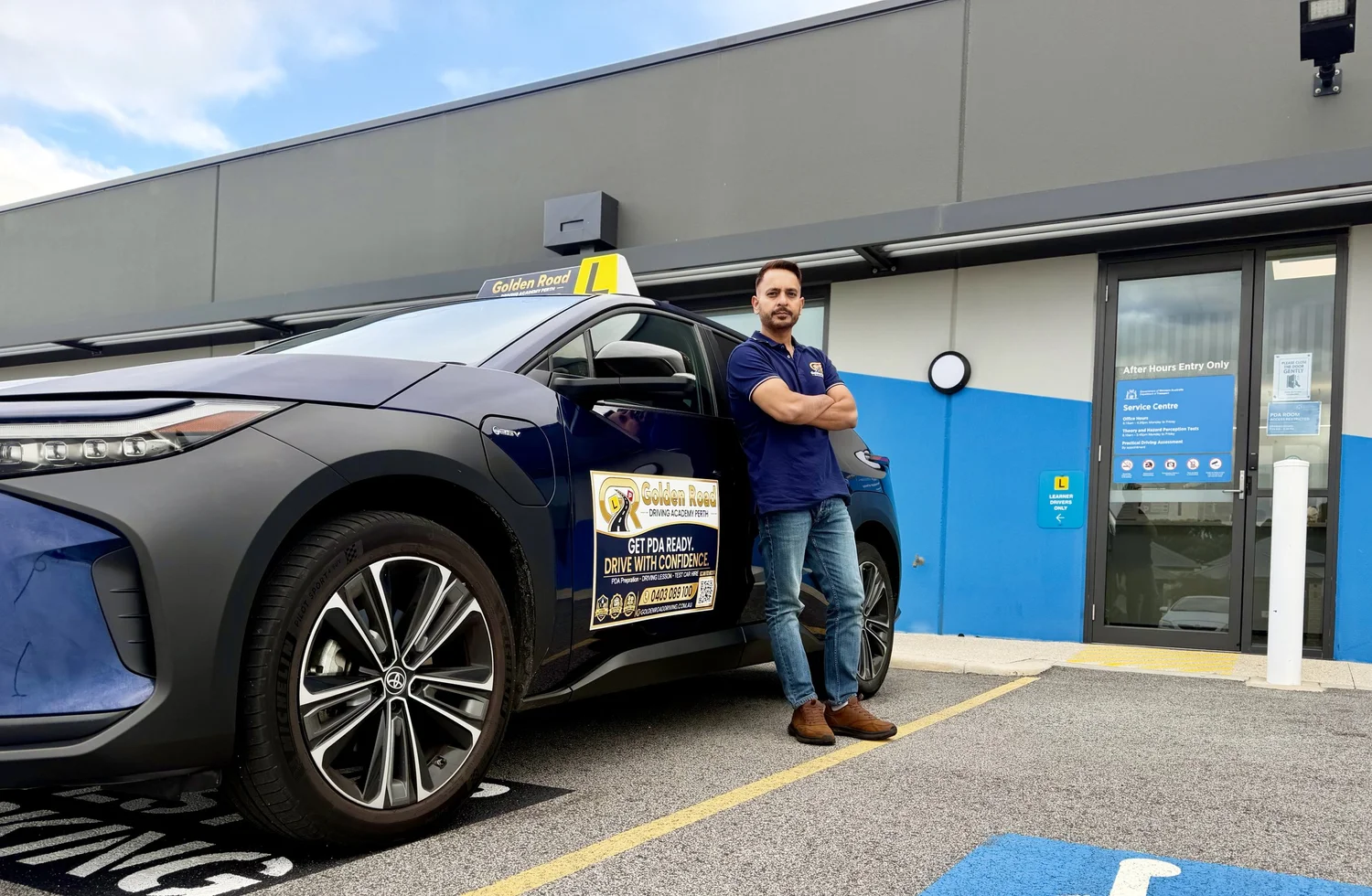 Paul Singh, founder of Golden Road Driving Academy, in uniform beside the branded lesson car at the entry of the Butler DoT licensing centre