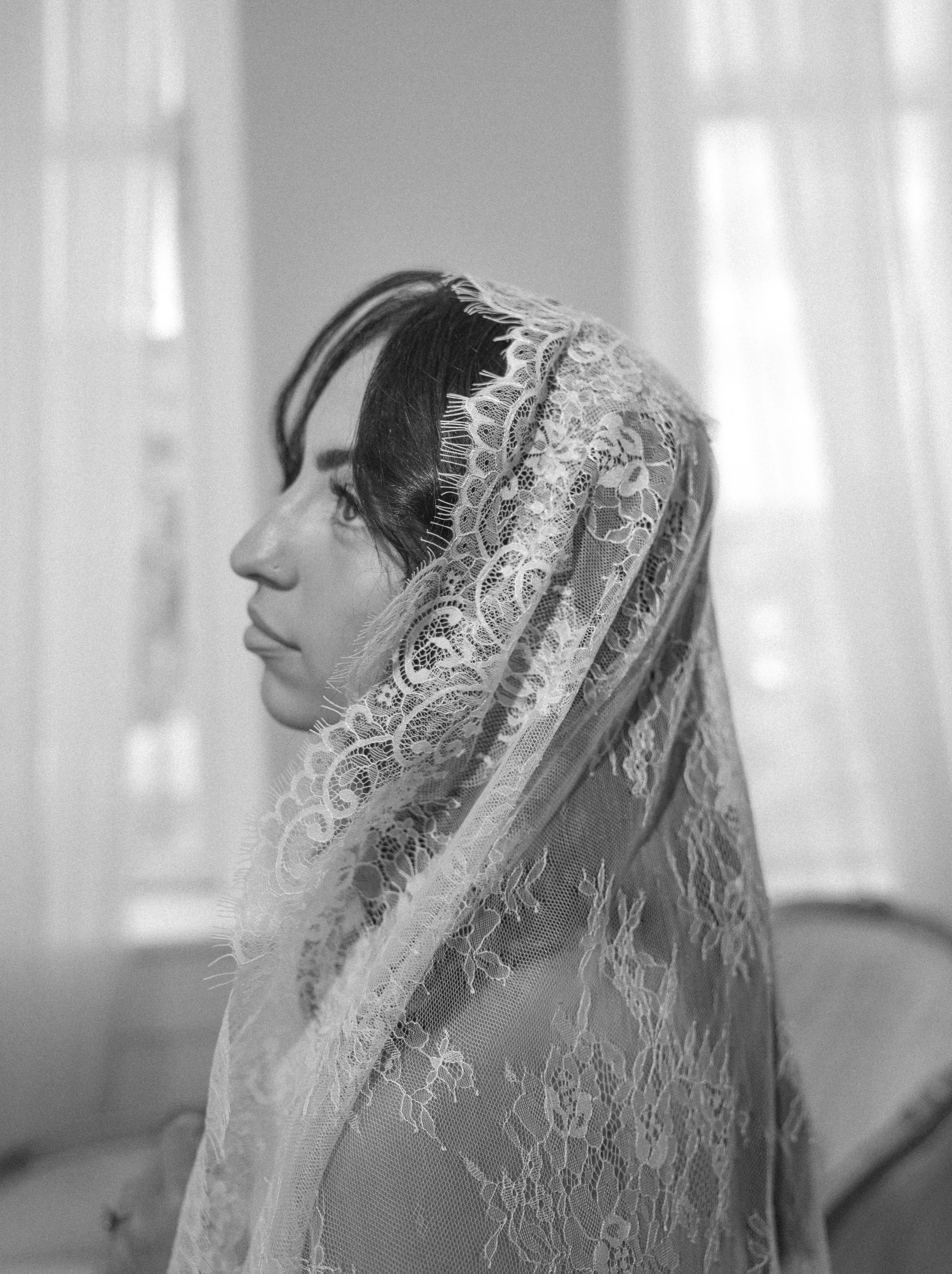Side profile of a woman with long hair, wearing a lace veil