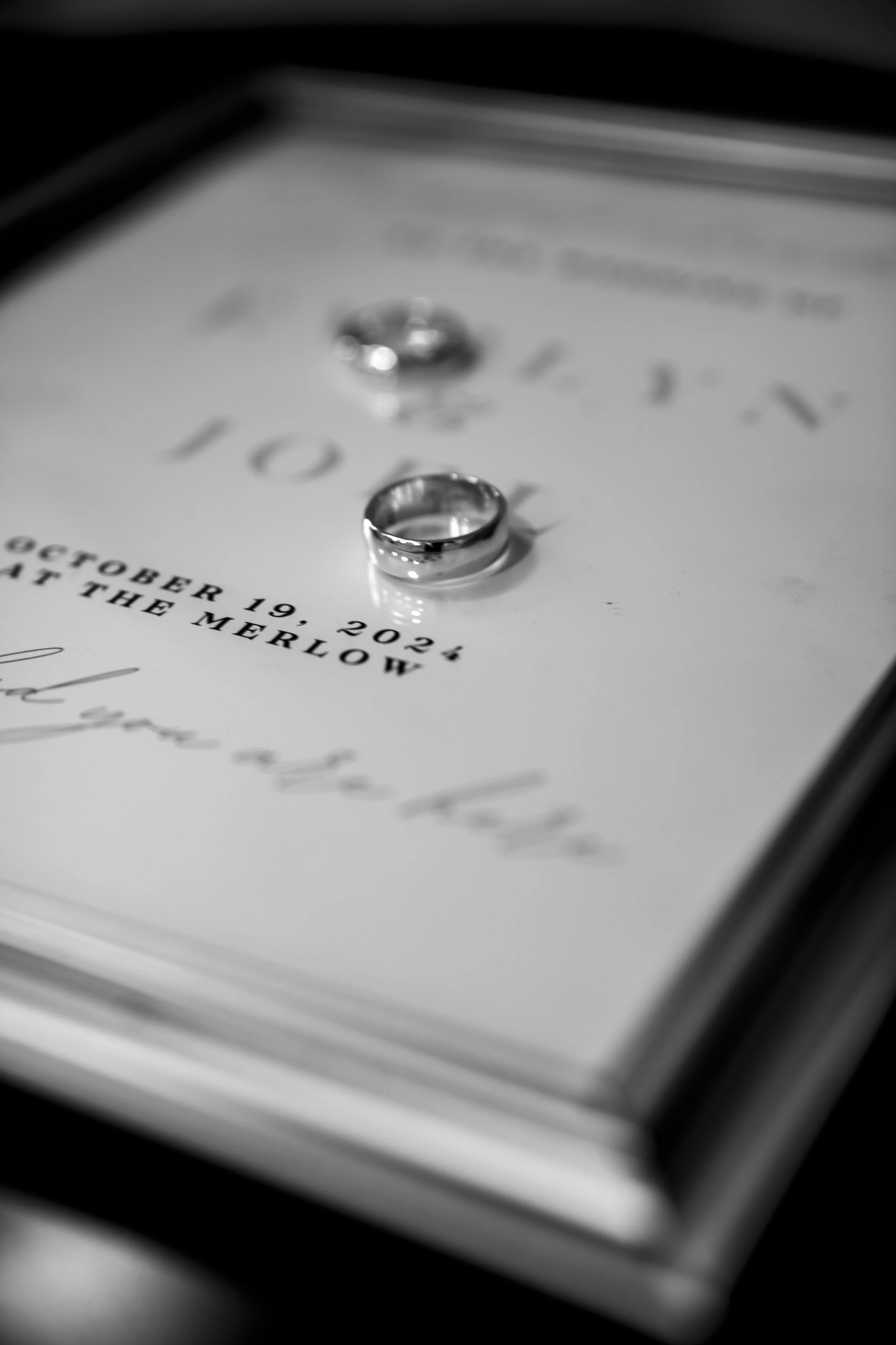 Wedding rings placed on a wedding invitation with black and white filter.