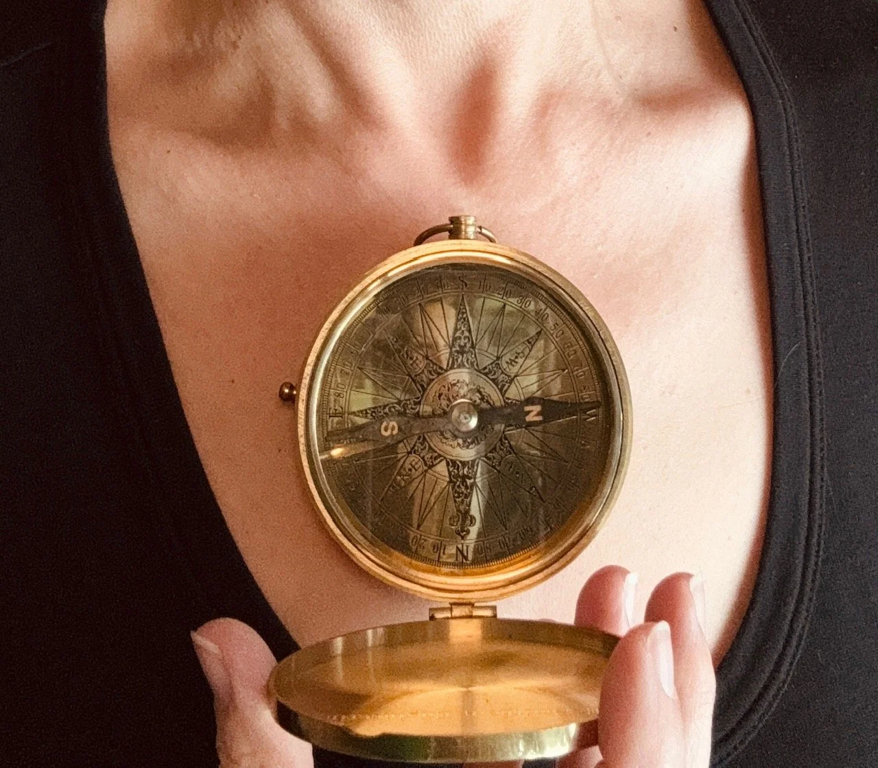 A beautiful woman holding an open compass on her chest