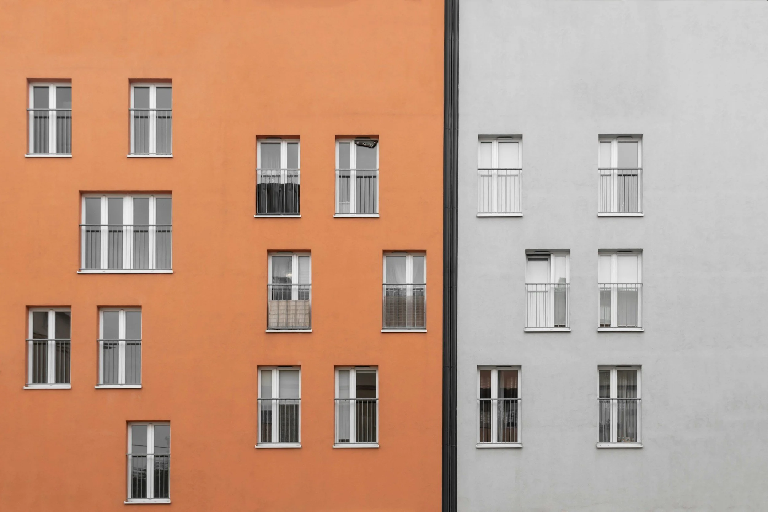 Two adjoining building façades in contrasting neutral tones, suggesting clarity and distinction.