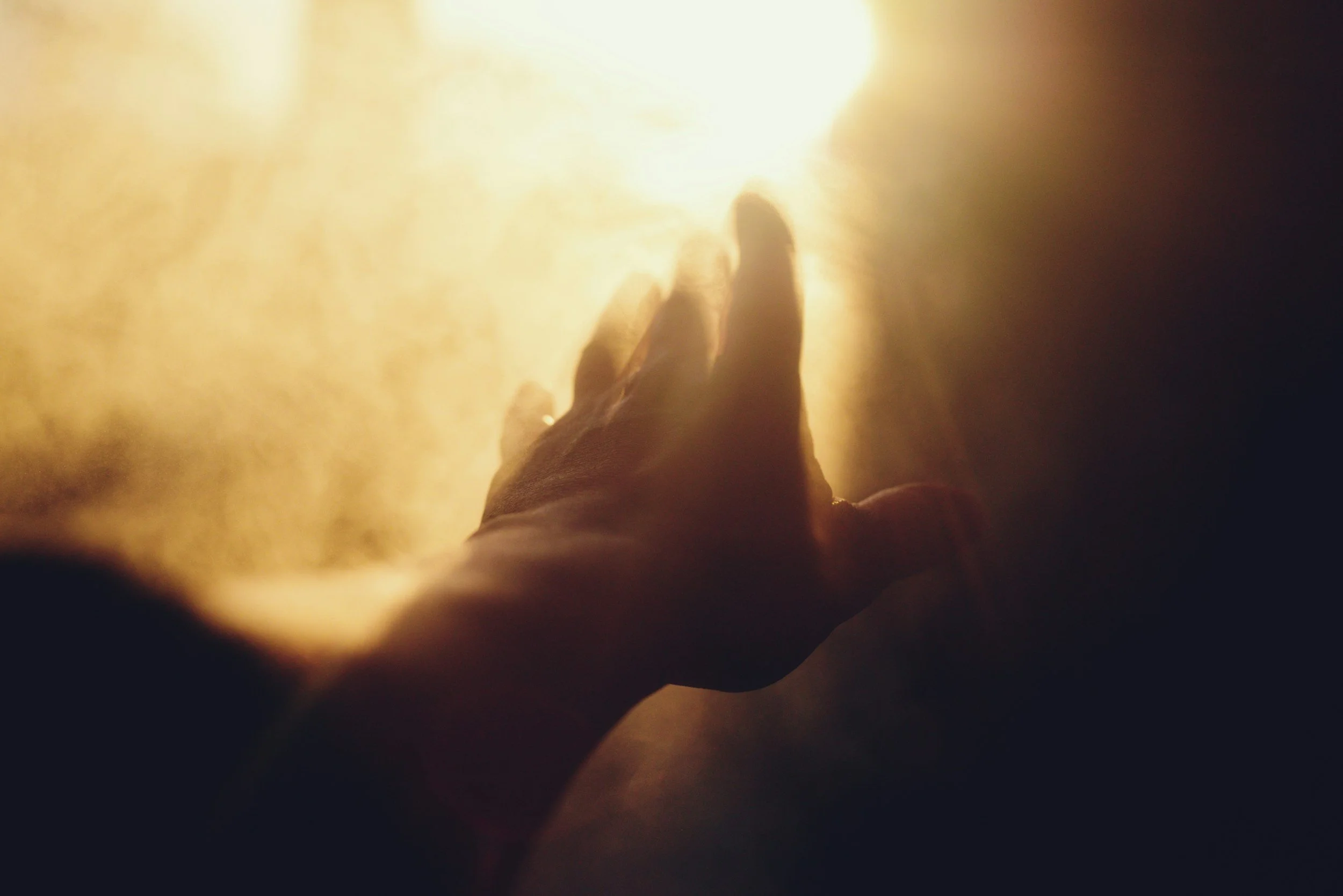 Hand reaching toward bright light representing psychological insight and the challenge of translating understanding into emotional change