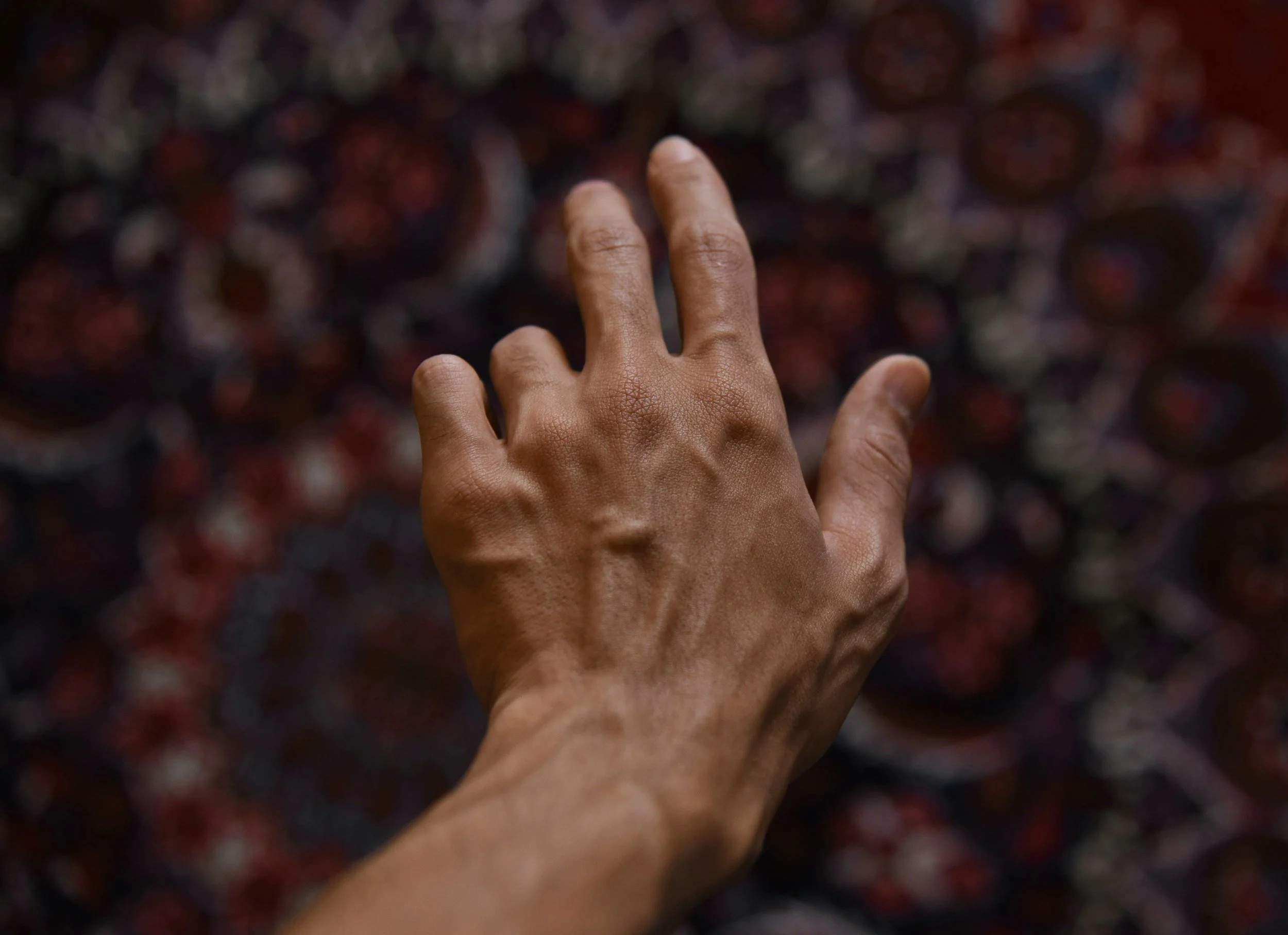 Hand reaching across a patterned background symbolising repeating emotional patterns in relationships