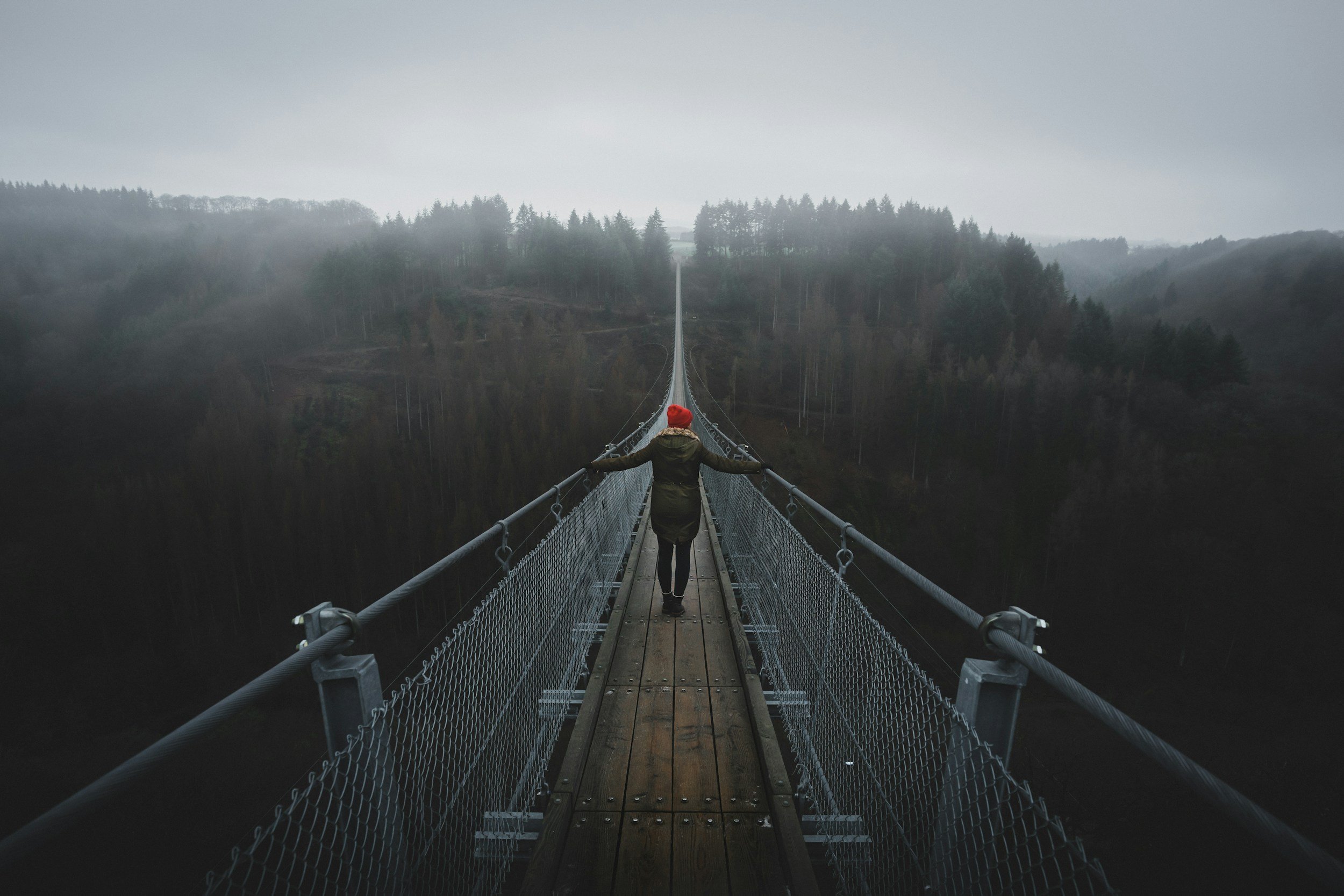 person walking across a suspension bridge in mist symbolising the emotional journey of depth-oriented therapy