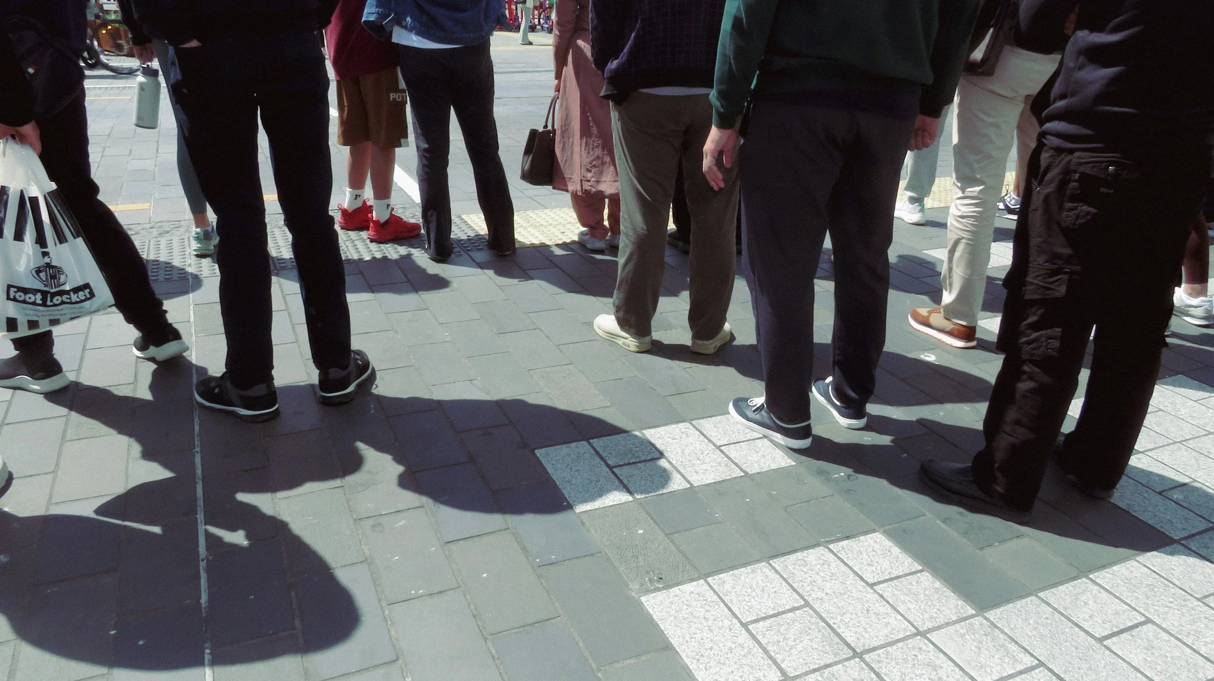 people standing together at a pedestrian crossing representing automatic behavioural patterns and repetition