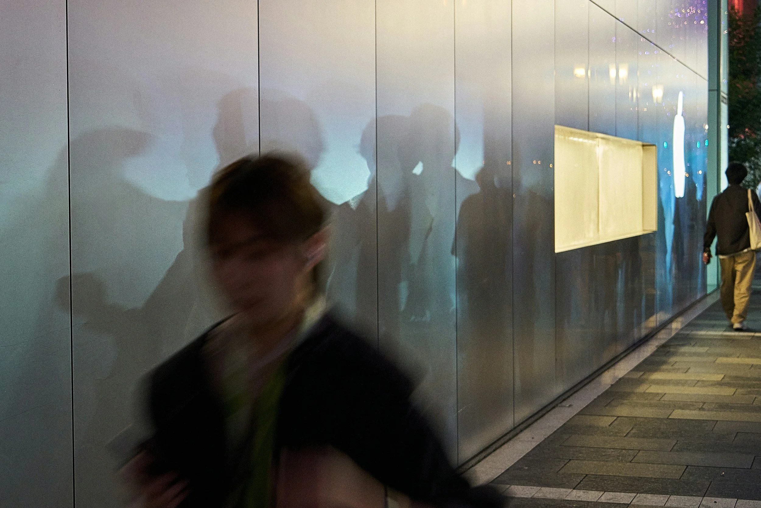 blurred person walking past reflective wall with multiple shadows symbolising psychological reflection and integration