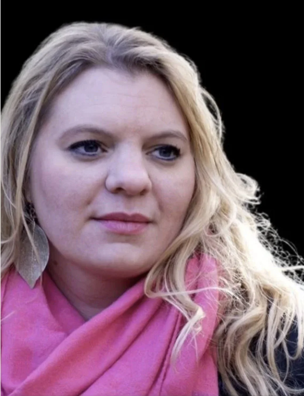Close-up image of a woman with blonde, curly hair wearing a pink scarf and a large, leaf-shaped earring.