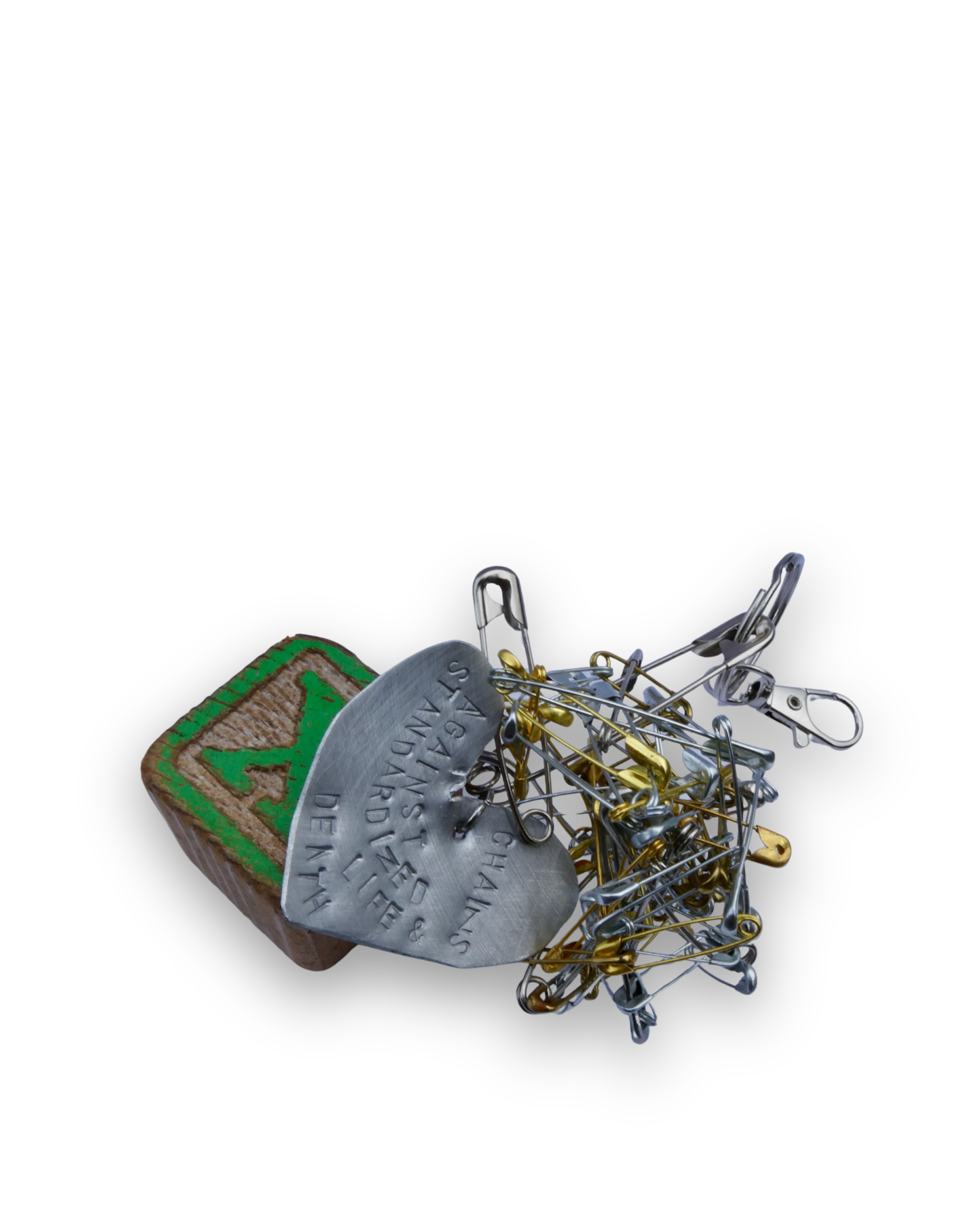 A cluster of safety pins, a metal tag with embossed text, and a wooden matchbox with green label on a black background.