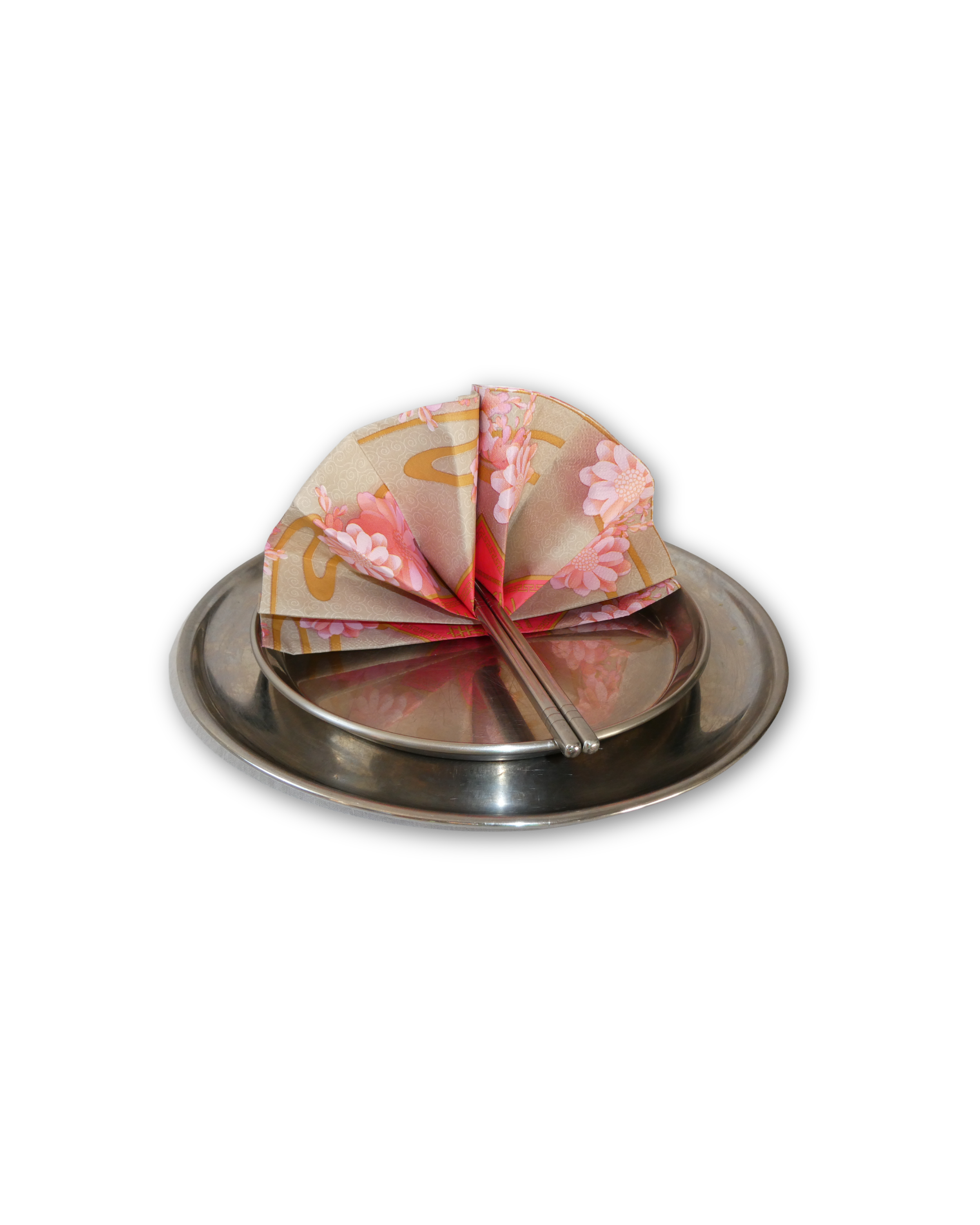 A silver serving tray with pink floral napkin folded into a fan shape and two metal chopsticks resting on it, set against a black background.