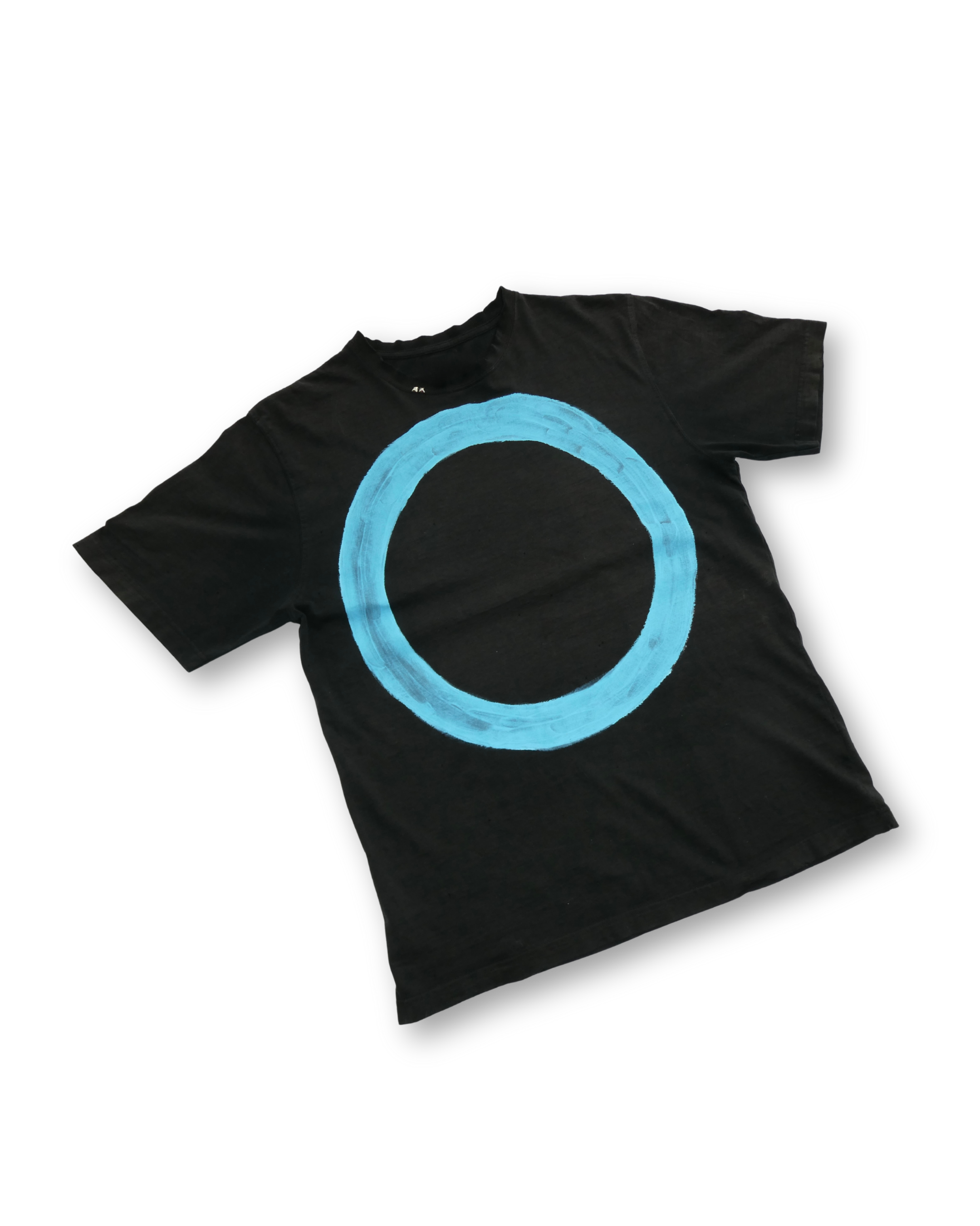 Black T-shirt with a large blue circle painted on it, laid flat on a black background.