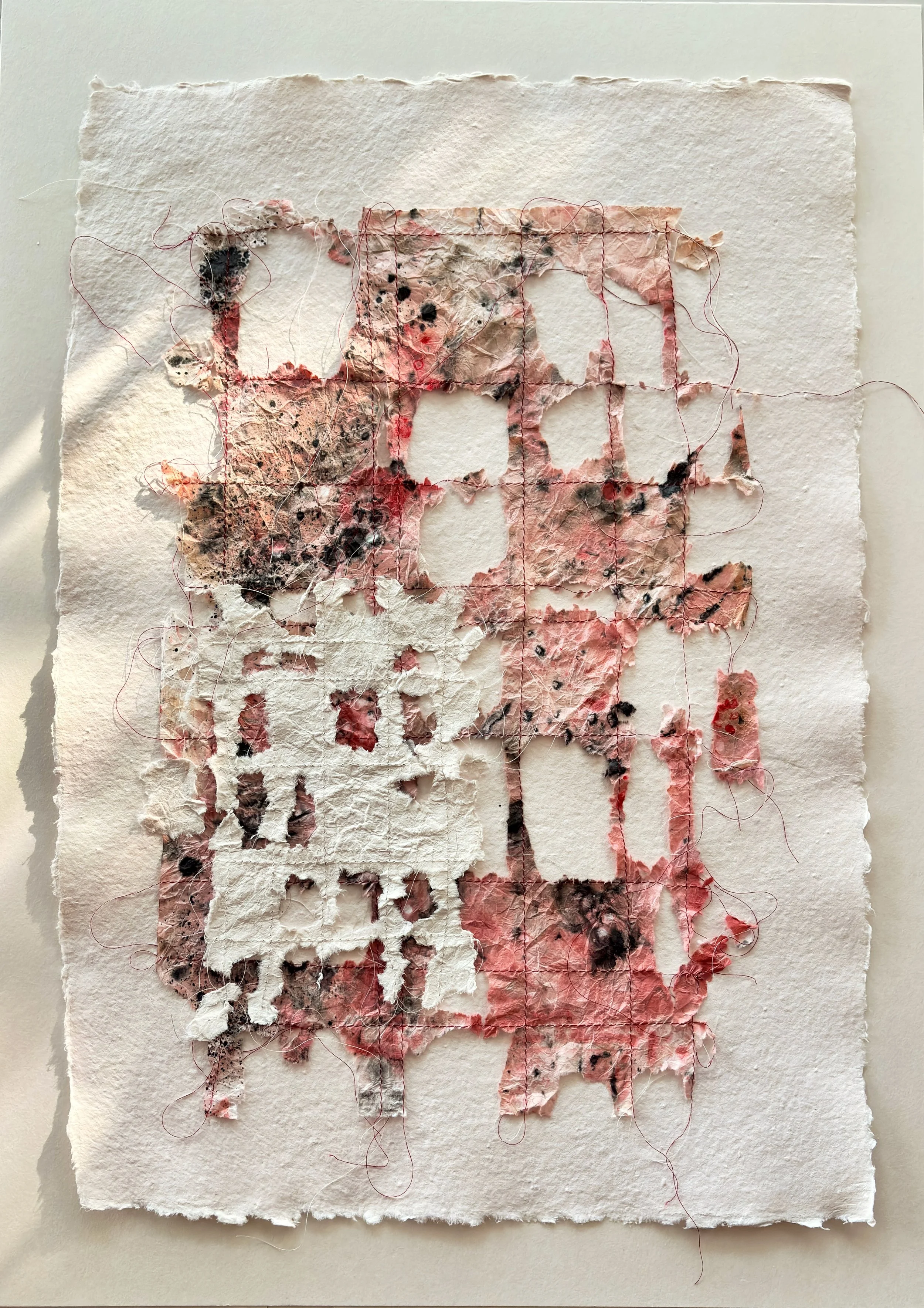 Mixed media abstract art on textured paper with torn edges, featuring stitched outlines and splashes of pink, black, and white colors.