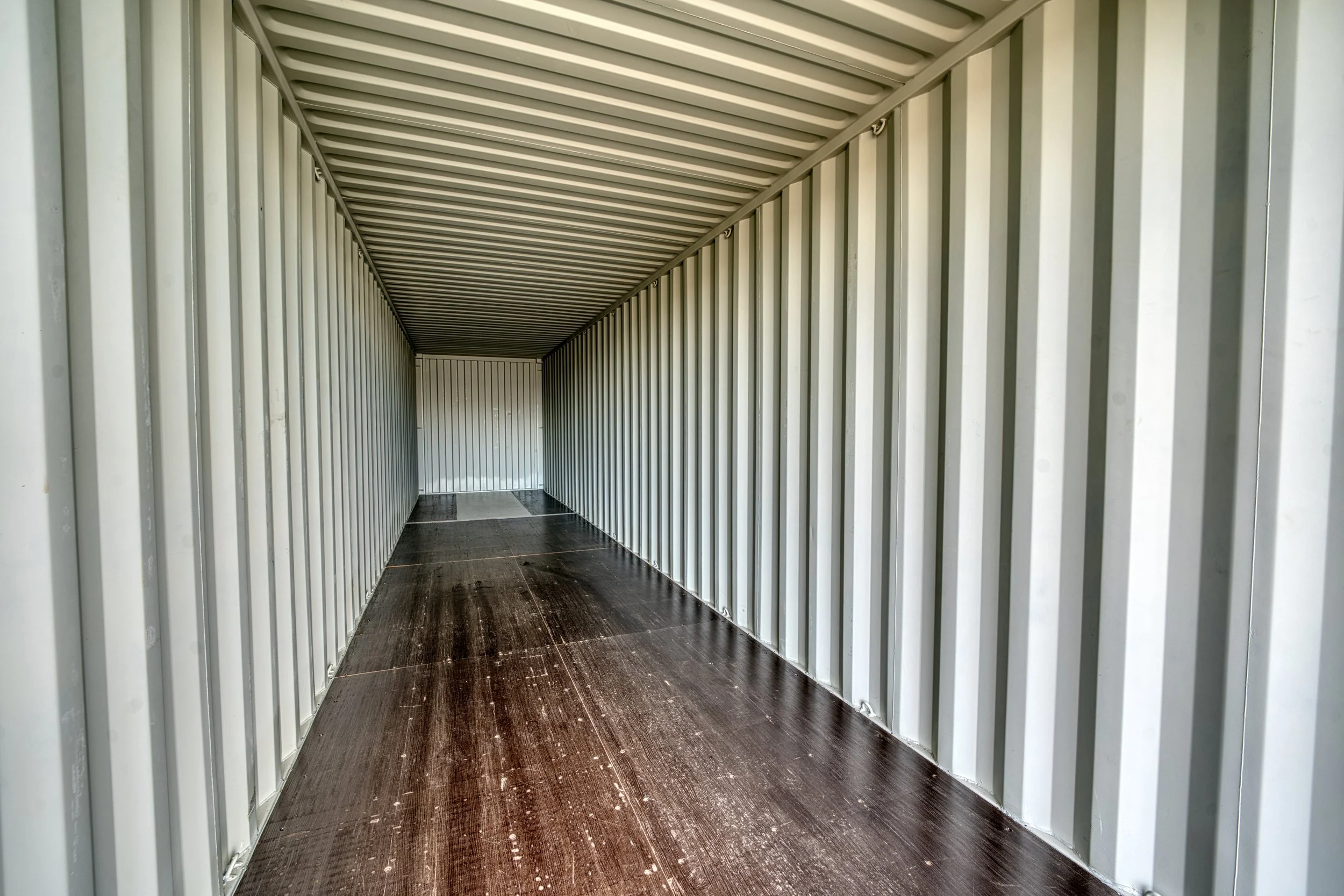 Empty indoor shipping container with wooden floor and metal walls.
