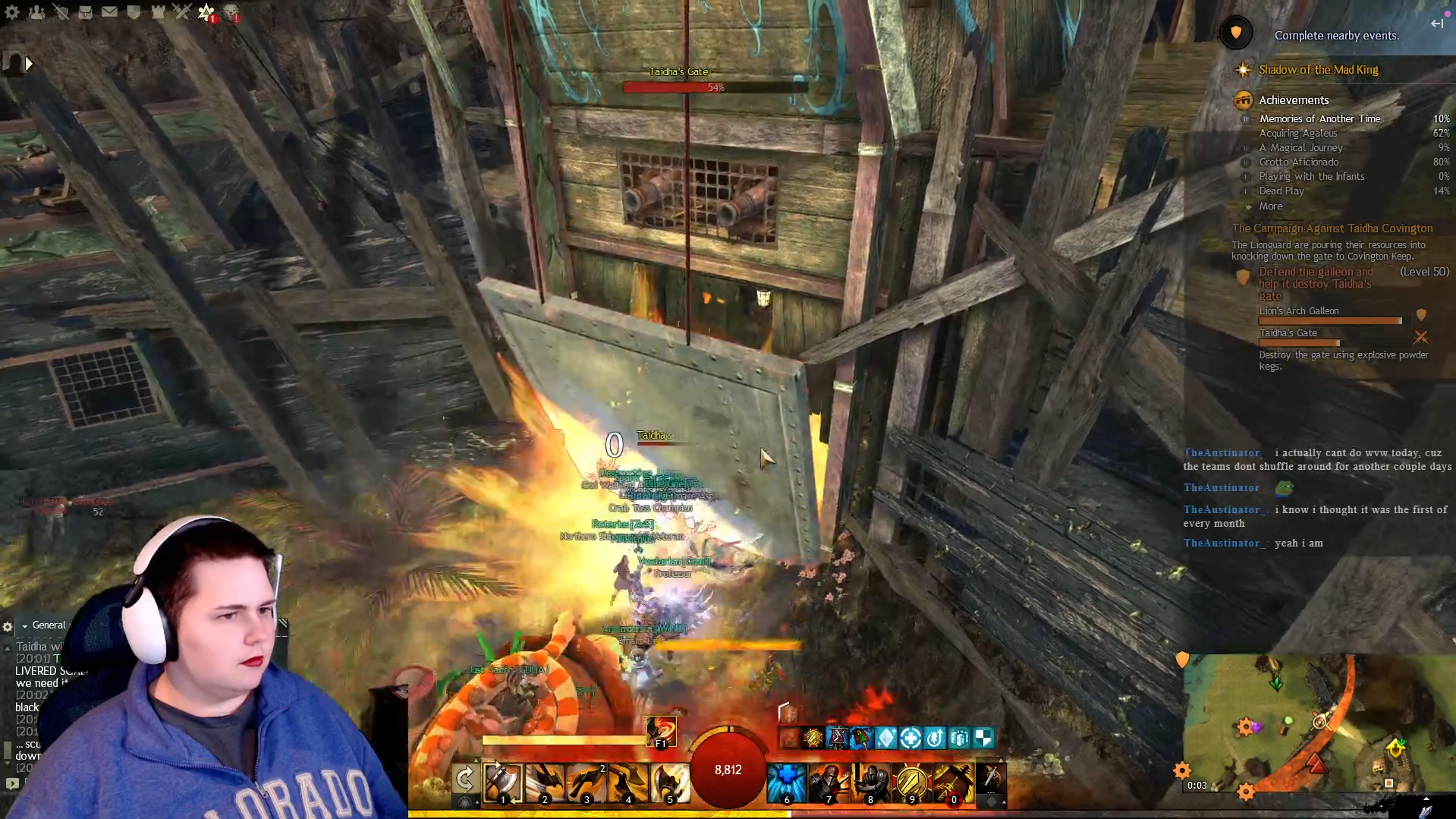 Screenshot of a video game showing a player fighting in a colorful, chaotic environment with wooden structures. The player's face and hand are visible in the lower left corner, and she has short dark hair and is wearing a blue jacket. The gaming interface displays health, skills, and chat messages on the right side of the screen, and a mini-map is present in the bottom right corner.