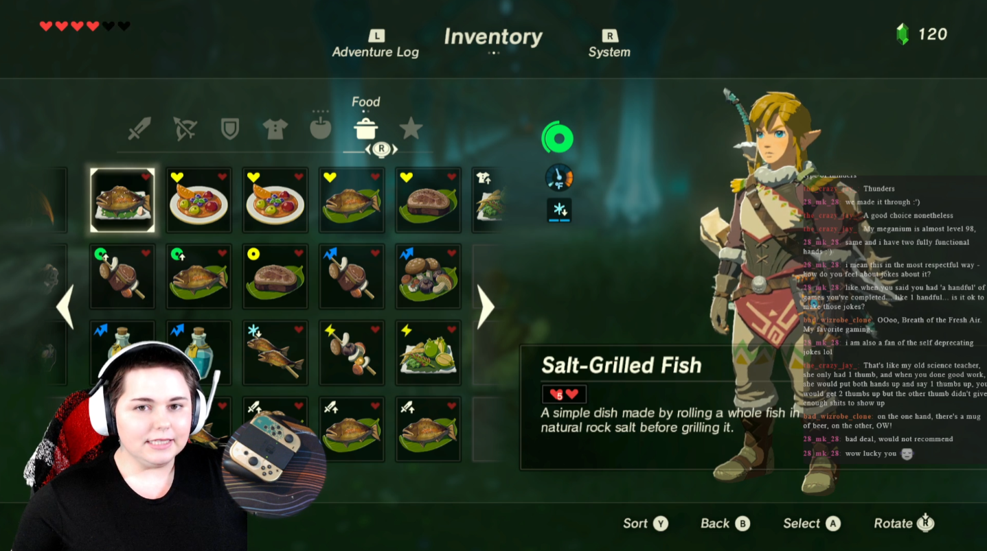 Screenshot from a video game showing an inventory menu with various food items, a character from the game (Link), and a chat box with player messages. There is also a person wearing headphones and a black shirt with a red and black blanket on the chair.