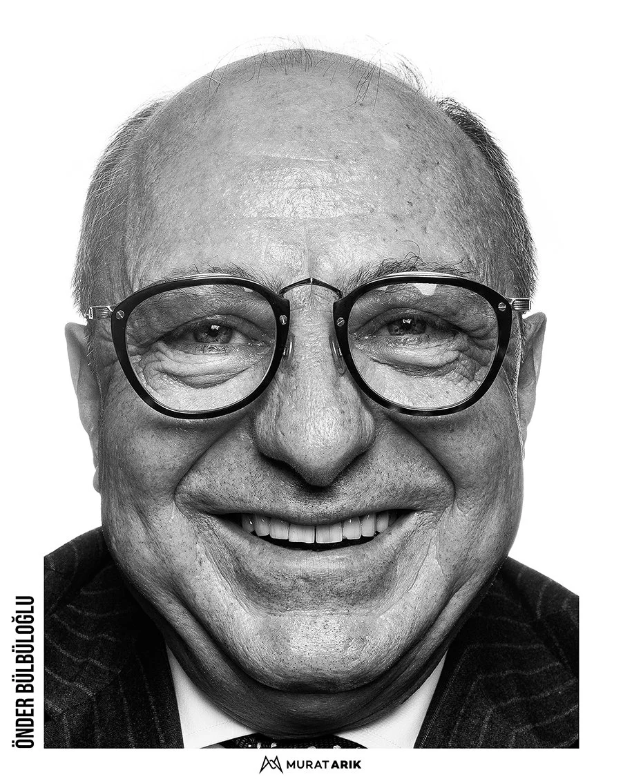 Black and white close-up portrait of an elderly man with glasses smiling.