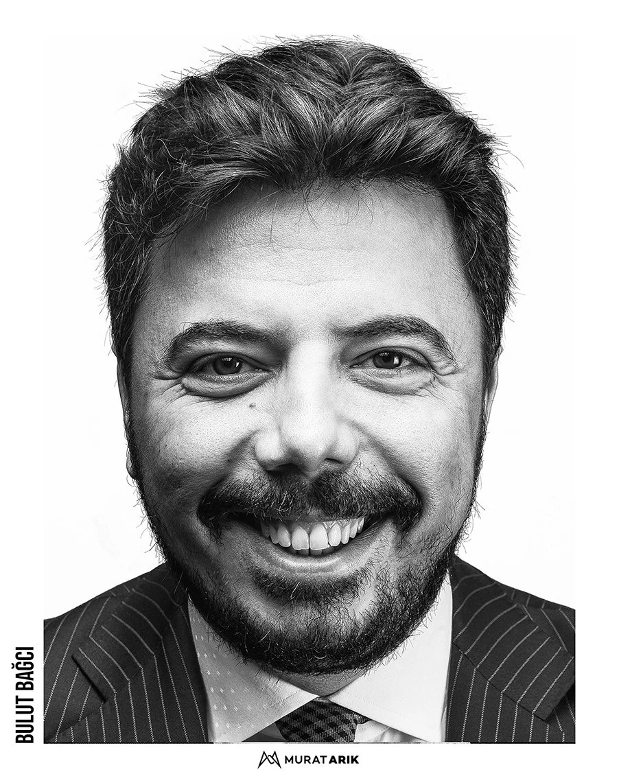 Black and white portrait of a man smiling, wearing a suit and tie.