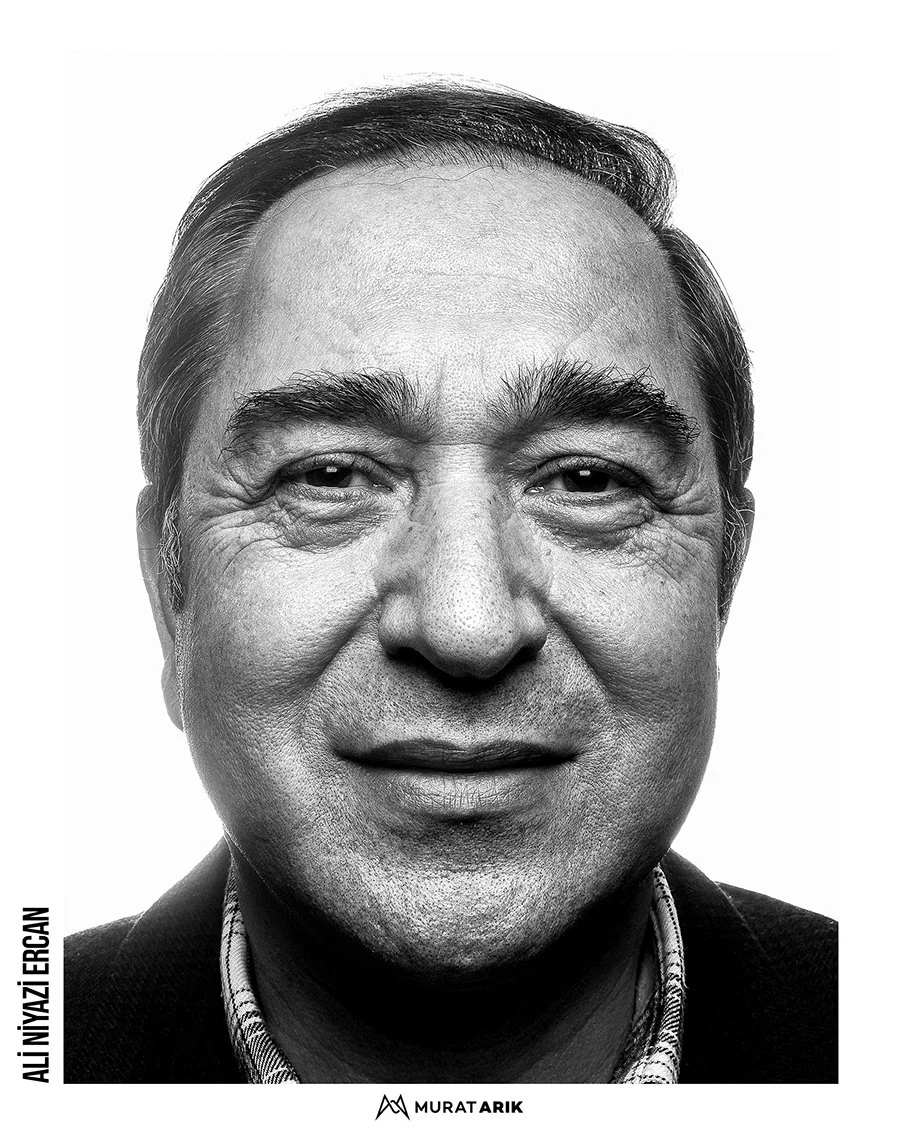 Close-up black and white portrait of a middle-aged man with dark hair, bushy eyebrows, and a slight smile.