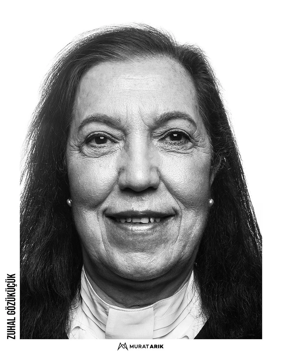 Black and white portrait of a smiling woman with long dark hair, wearing earrings and clerical collar.
