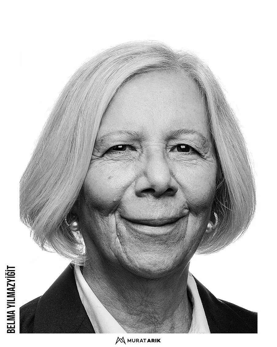 Black and white portrait of an older woman with shoulder-length hair, wearing earrings and a blazer, smiling slightly.