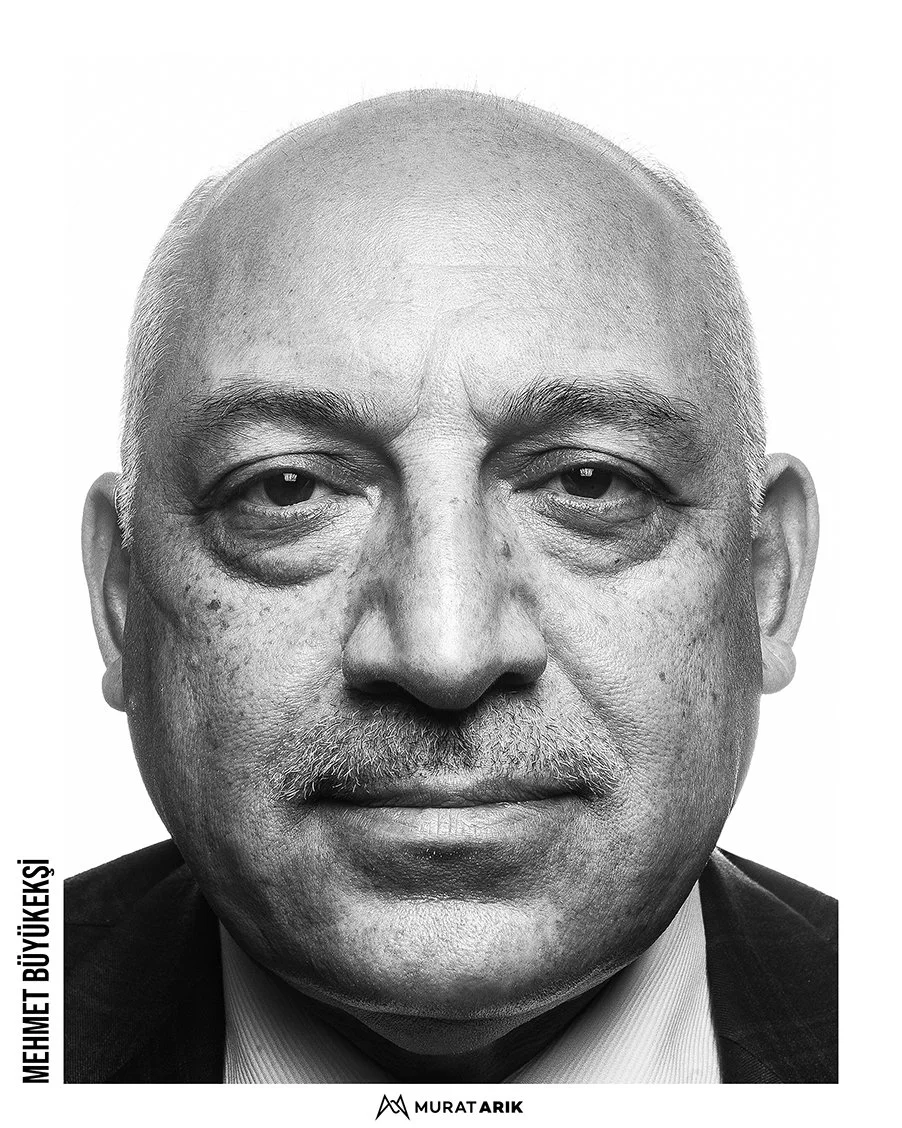 Black and white close-up portrait of an older man with a bald head and a mustache, wearing a suit and tie.