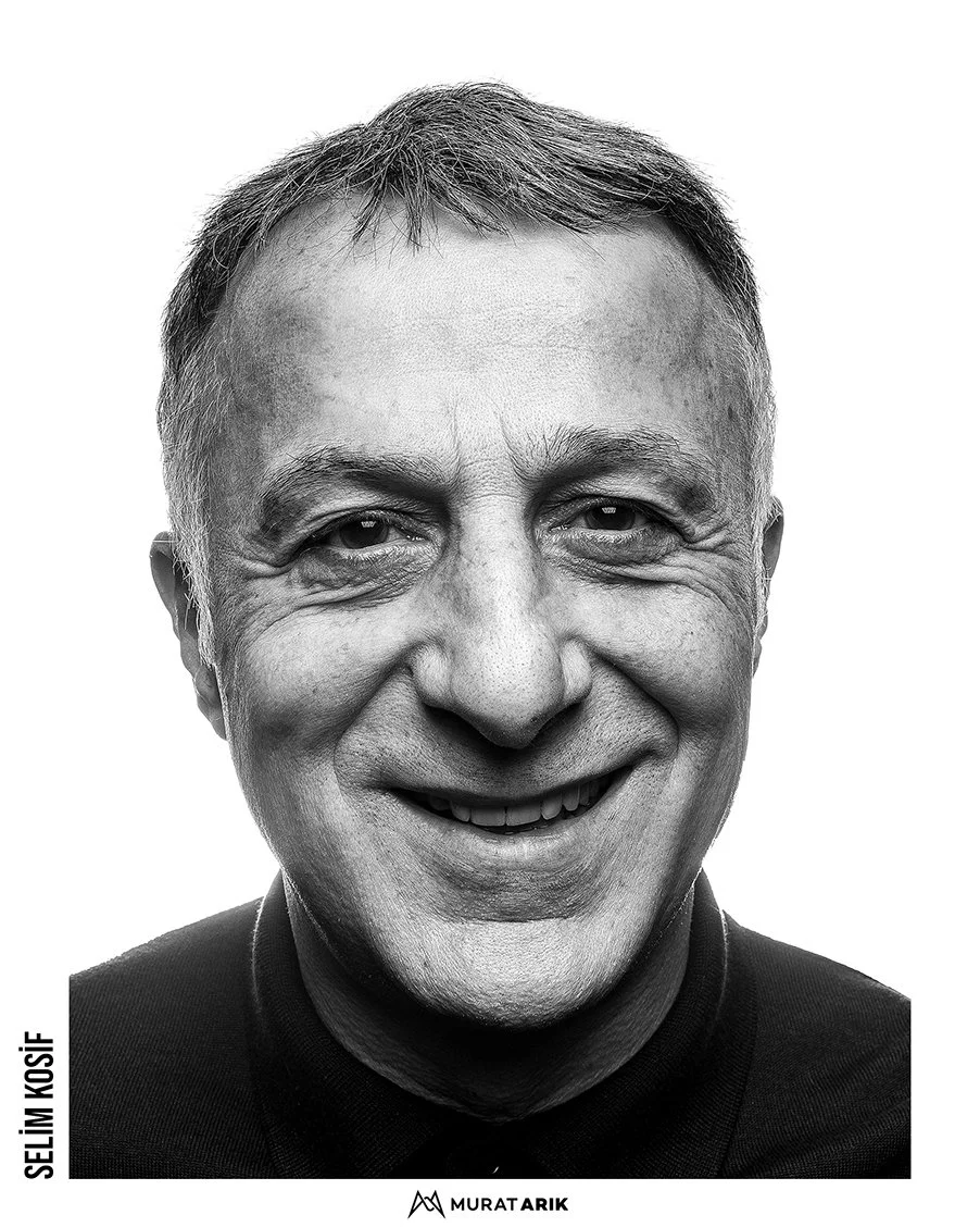 Black and white close-up portrait of a middle-aged man smiling, with short hair and wearing a dark shirt.