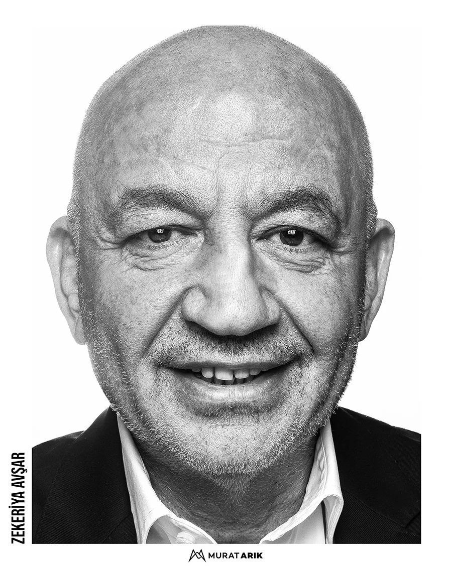 Black and white close-up portrait of an elderly man with a bald head and a friendly smile, wearing a suit.