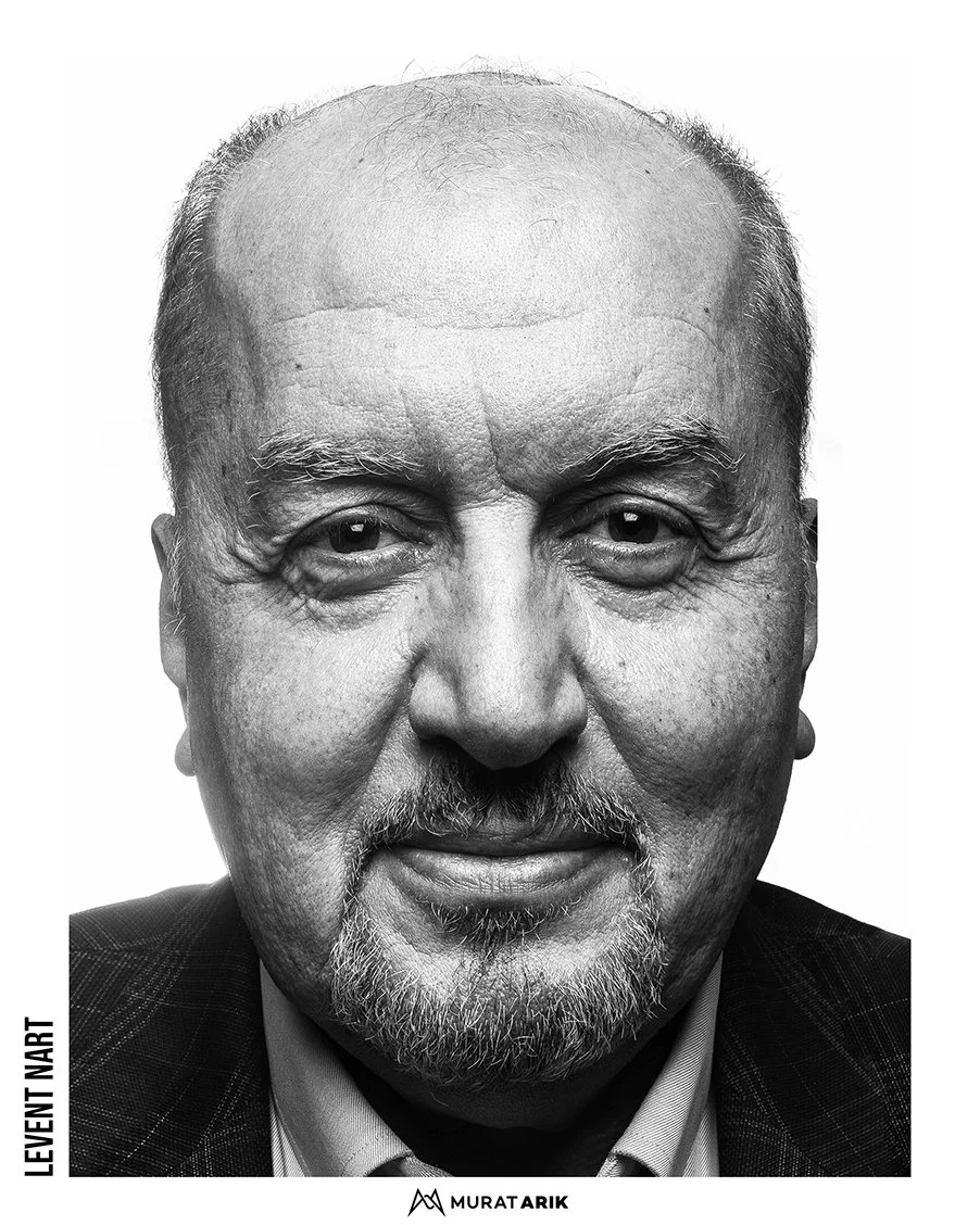 Black and white portrait of an elderly man with a bald head, gray beard, and expressive facial features, wearing a dark suit jacket.